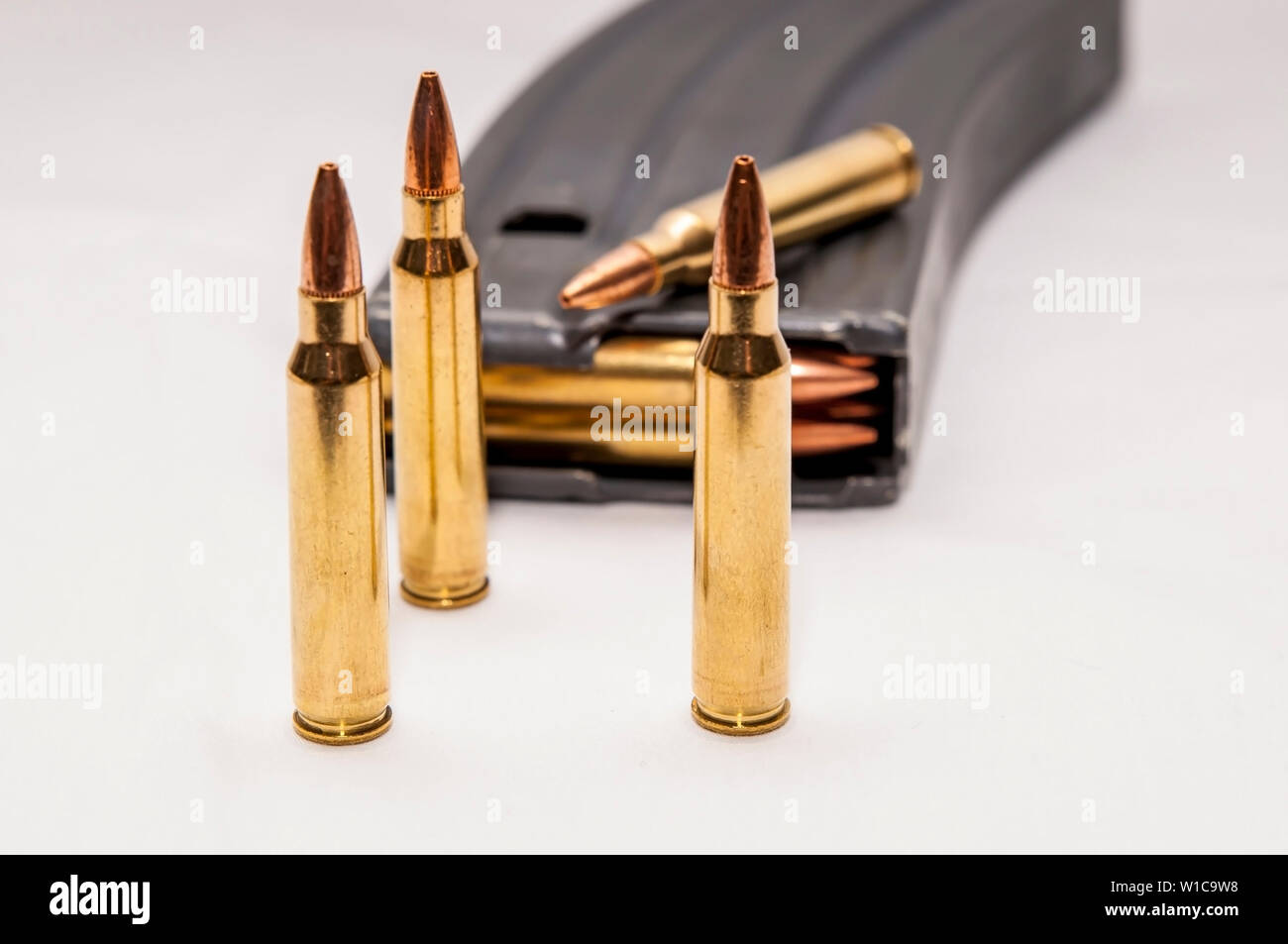 223 proiettili calibro lungo con un caricato 223 fucile calibro magazine su sfondo bianco Foto Stock