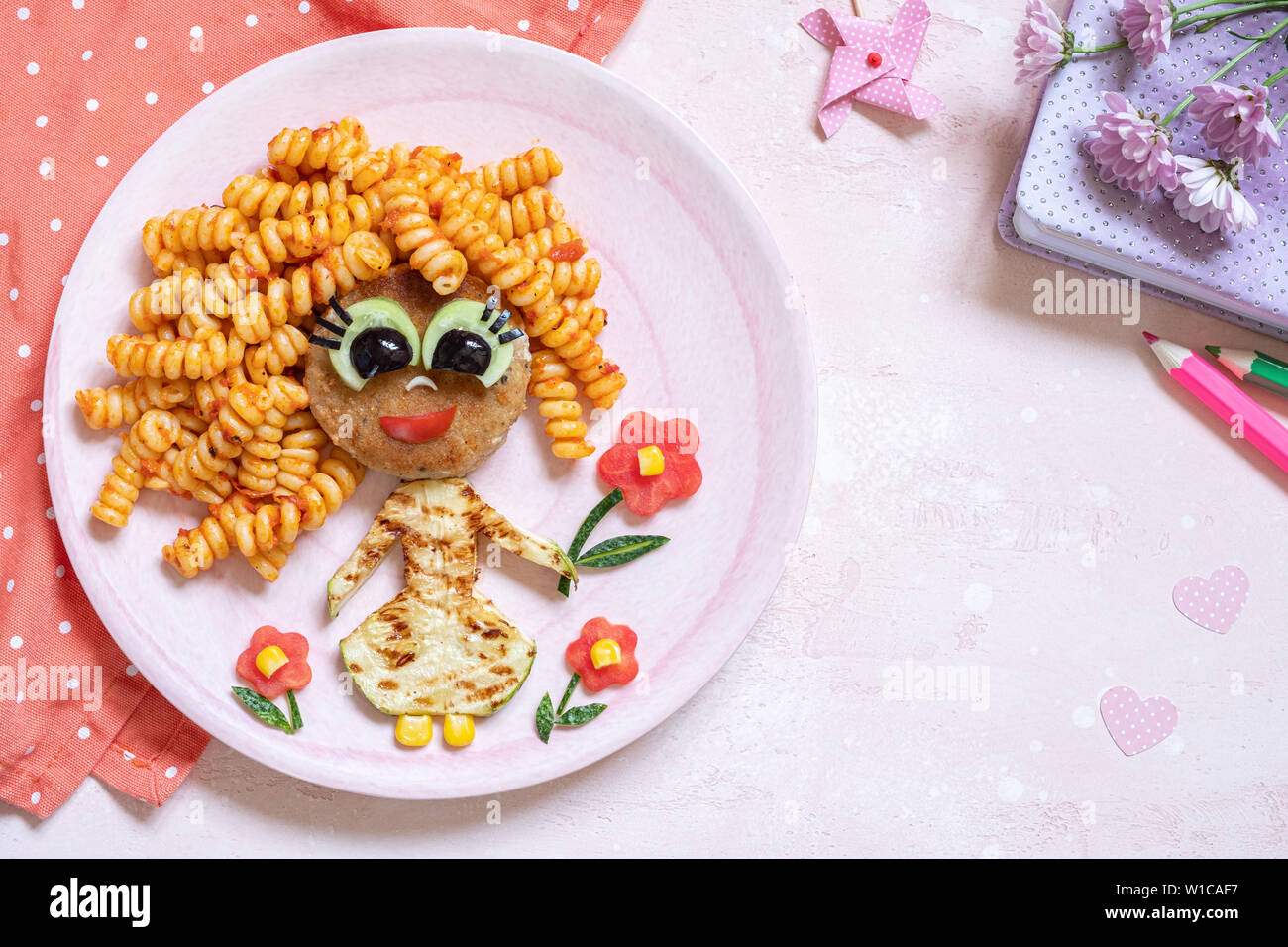 Funny Girl cibo faccia con cotoletta, pasta e verdure Foto Stock