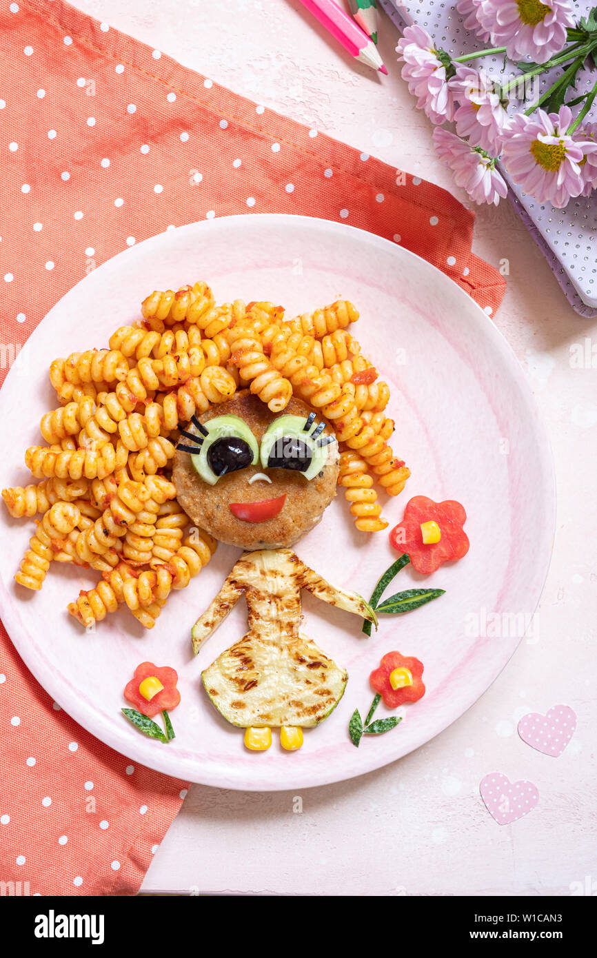 Funny Girl cibo faccia con cotoletta, pasta e verdure Foto Stock