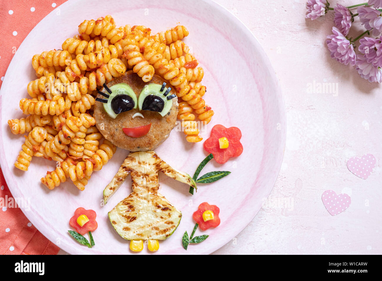 Funny Girl cibo faccia con cotoletta, pasta e verdure Foto Stock