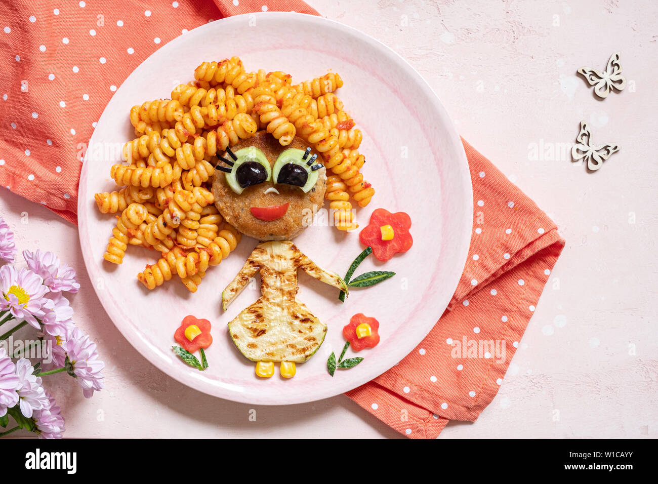 Funny Girl cibo faccia con cotoletta, pasta e verdure Foto Stock