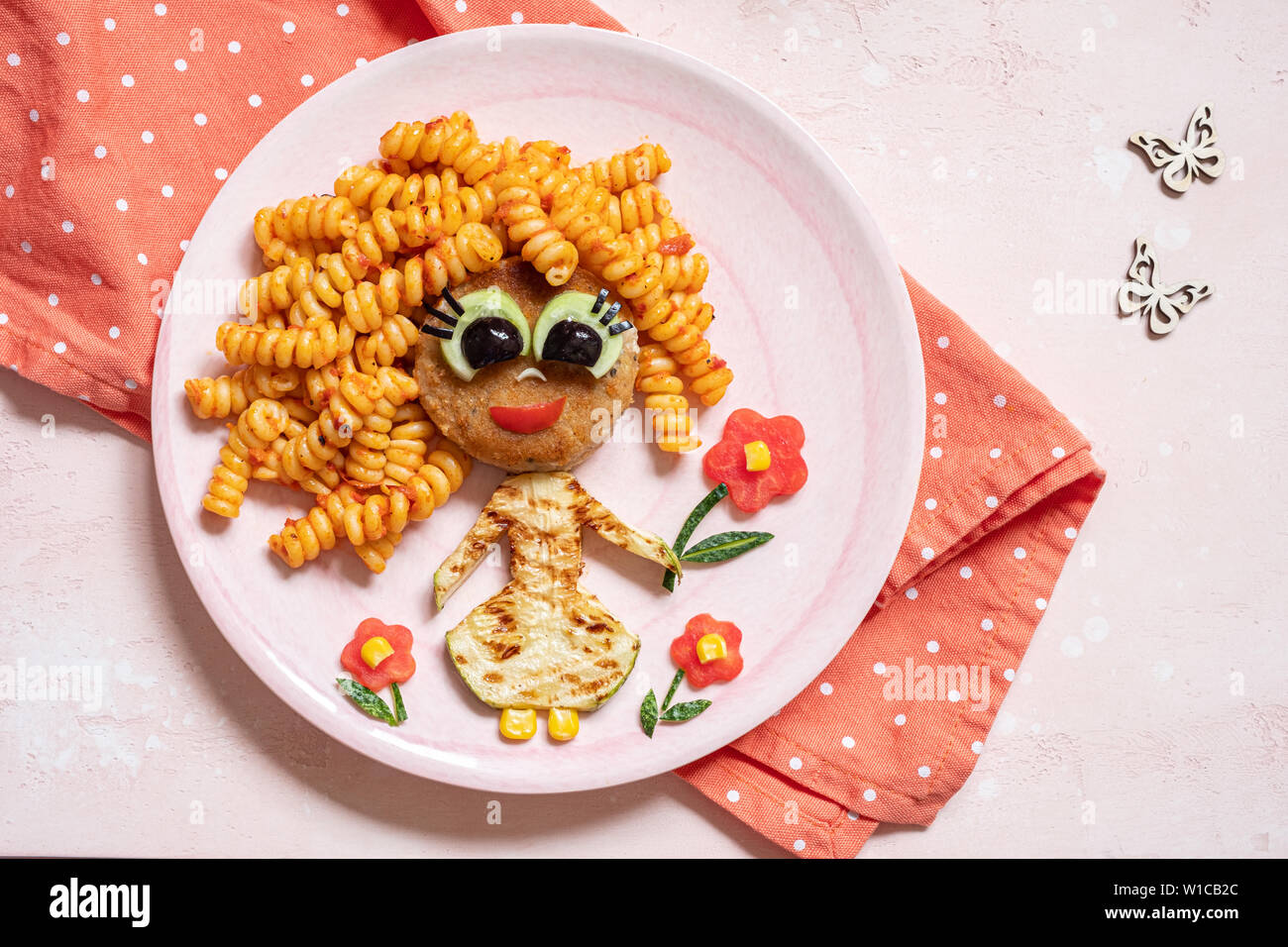 Funny Girl cibo faccia con cotoletta, pasta e verdure Foto Stock