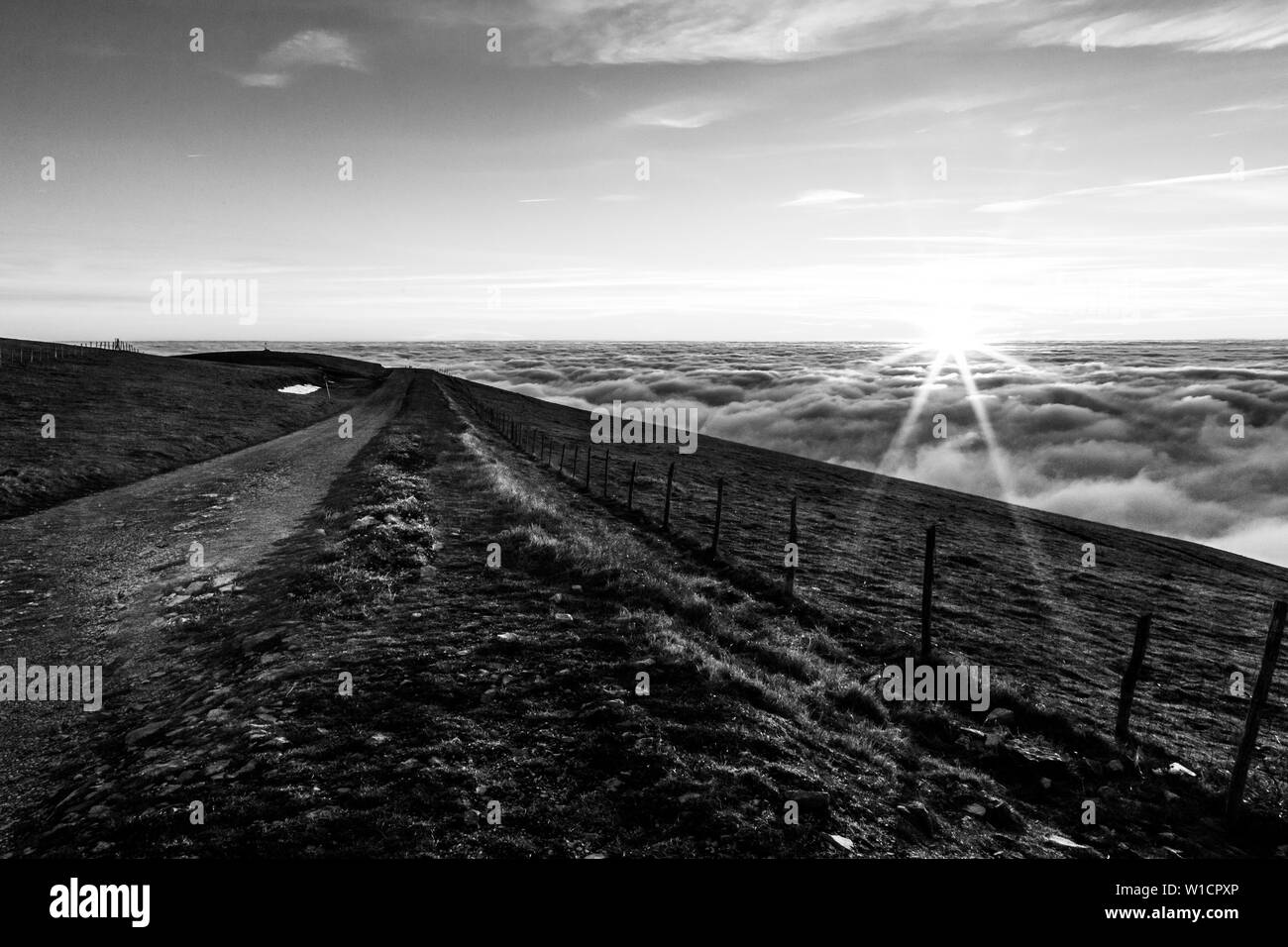 Tramonto su un mare di nebbia con una strada di montagna in primo piano sul Monte Subasio (Umbria, Italia) Foto Stock