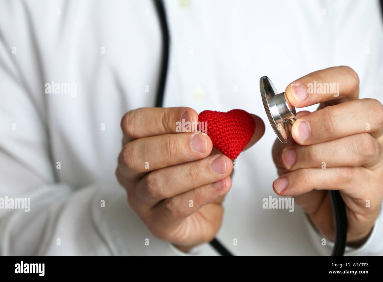 Medico con stetoscopio e maglia rossa cuore in mano. Concetto di cardiologo, le malattie di cuore, diagnosi, pressione sanguigna, medical exam Foto Stock