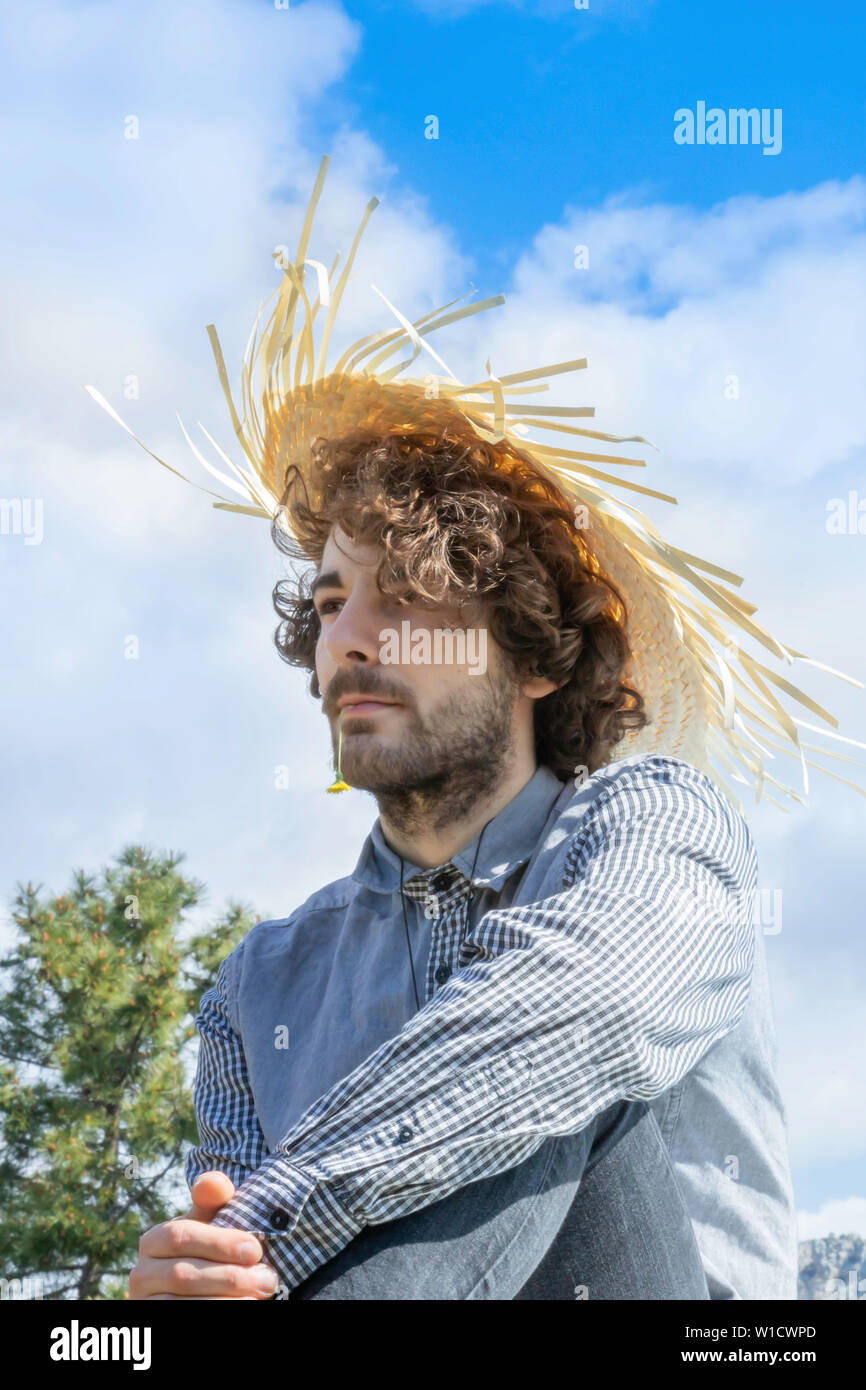 Giovane uomo adulto che guarda lontano, marrone capelli ricci con un West  Indian cappello di paglia sulla sua testa Foto stock - Alamy
