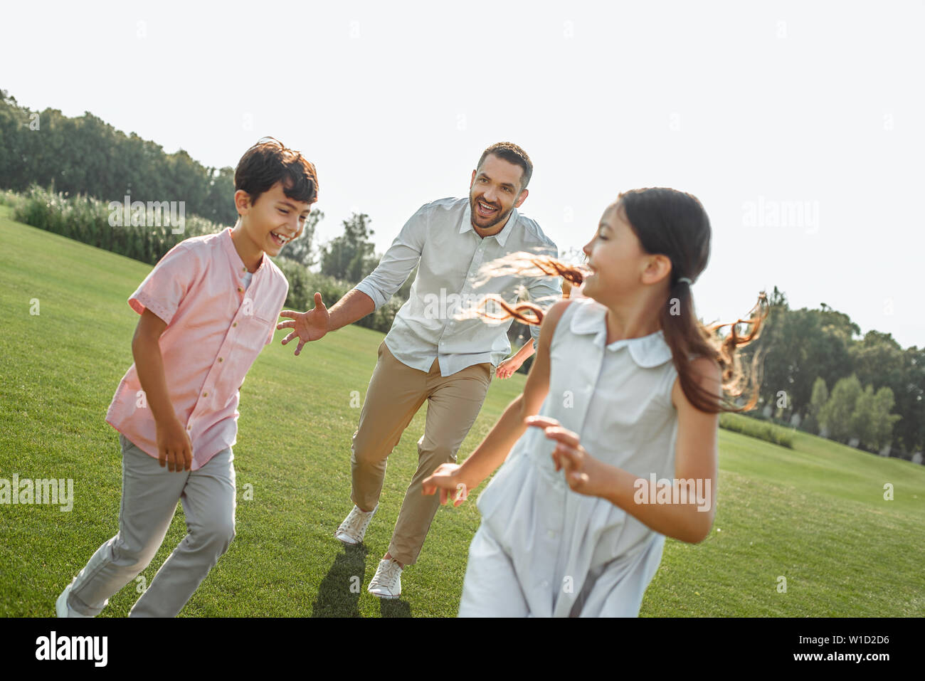 Giocando con il papà. Per tutta la lunghezza del padre a giocare con i suoi figli e sorridenti mentre spendere tempo libero all'esterno. Le attività di fine settimana Foto Stock