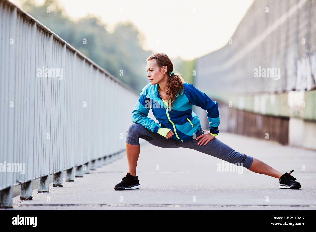 Giovane donna runner stretching gambe durante la corsa mattutina Foto Stock