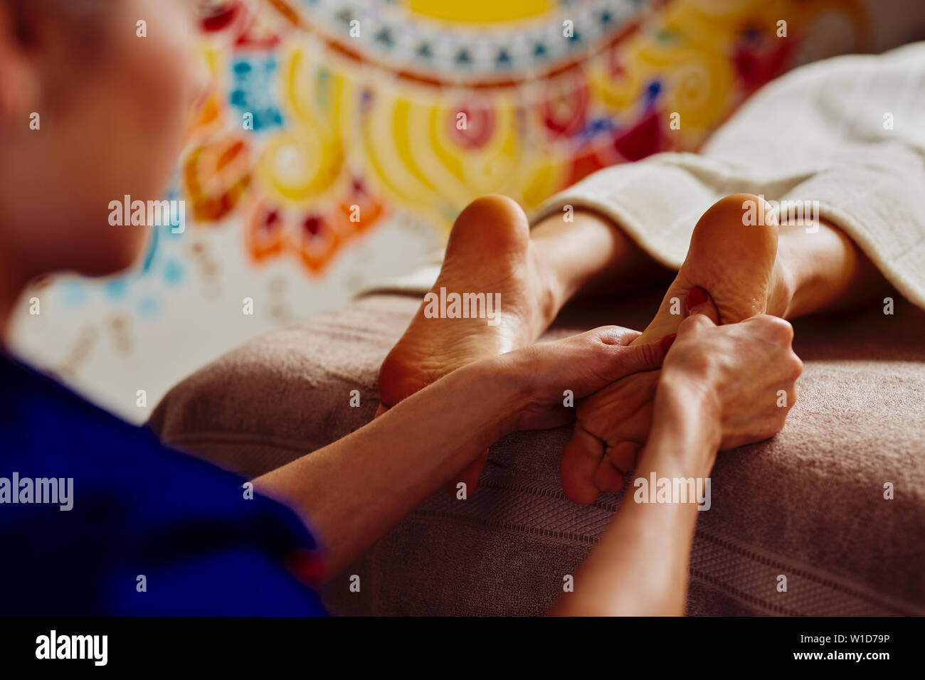 Primo piano della femmina terapista di massaggio piedi massaggio in colorate di un rilassante centro termale Foto Stock