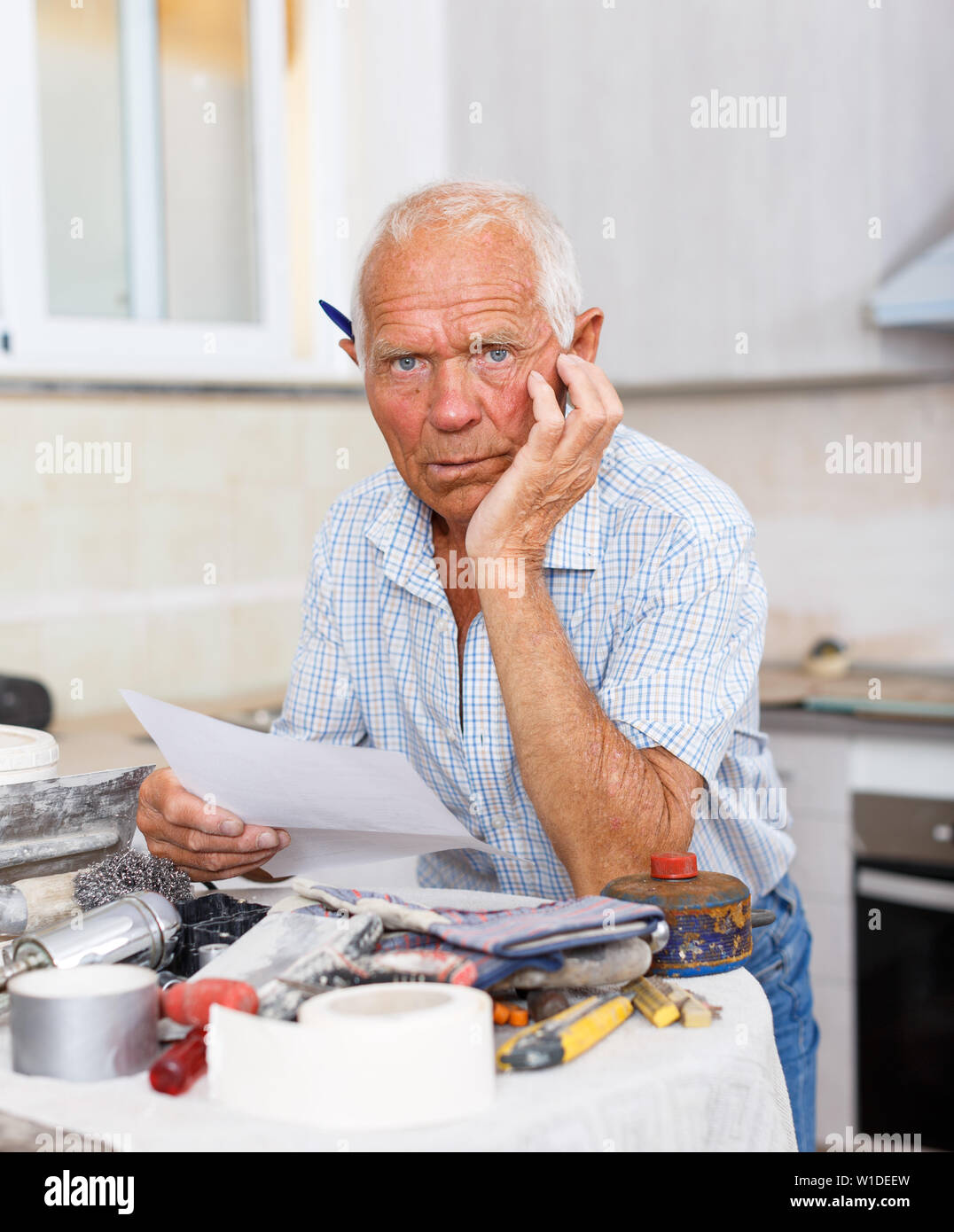 Malinconici uomo più anziano di pianificazione riparazioni imminenti, rendendo elenco opere Foto Stock