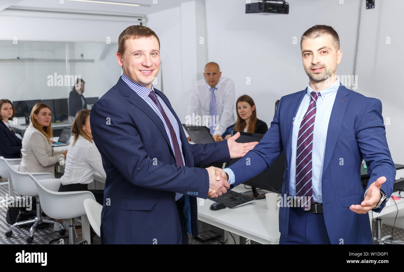 Due imprenditori fiducioso stringono le mani in office confermando partnership di successo Foto Stock