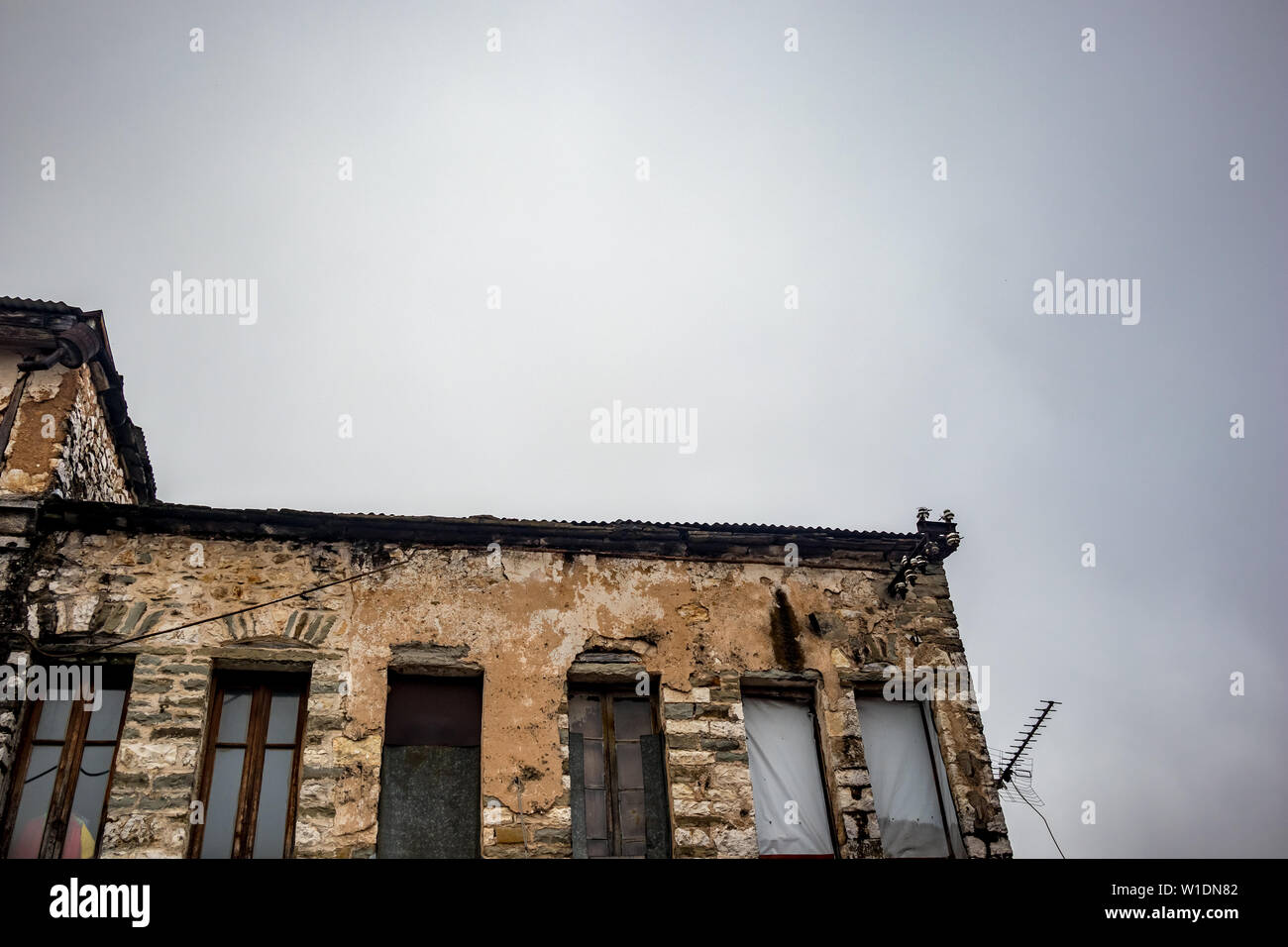 Il Greco antico edificio industriale in costruzione con mattoni visibile, centro di Ioannina, Grecia. Moody nebbiosa mattina di primavera, nessun popolo, rusty antenna TV silhouette Foto Stock