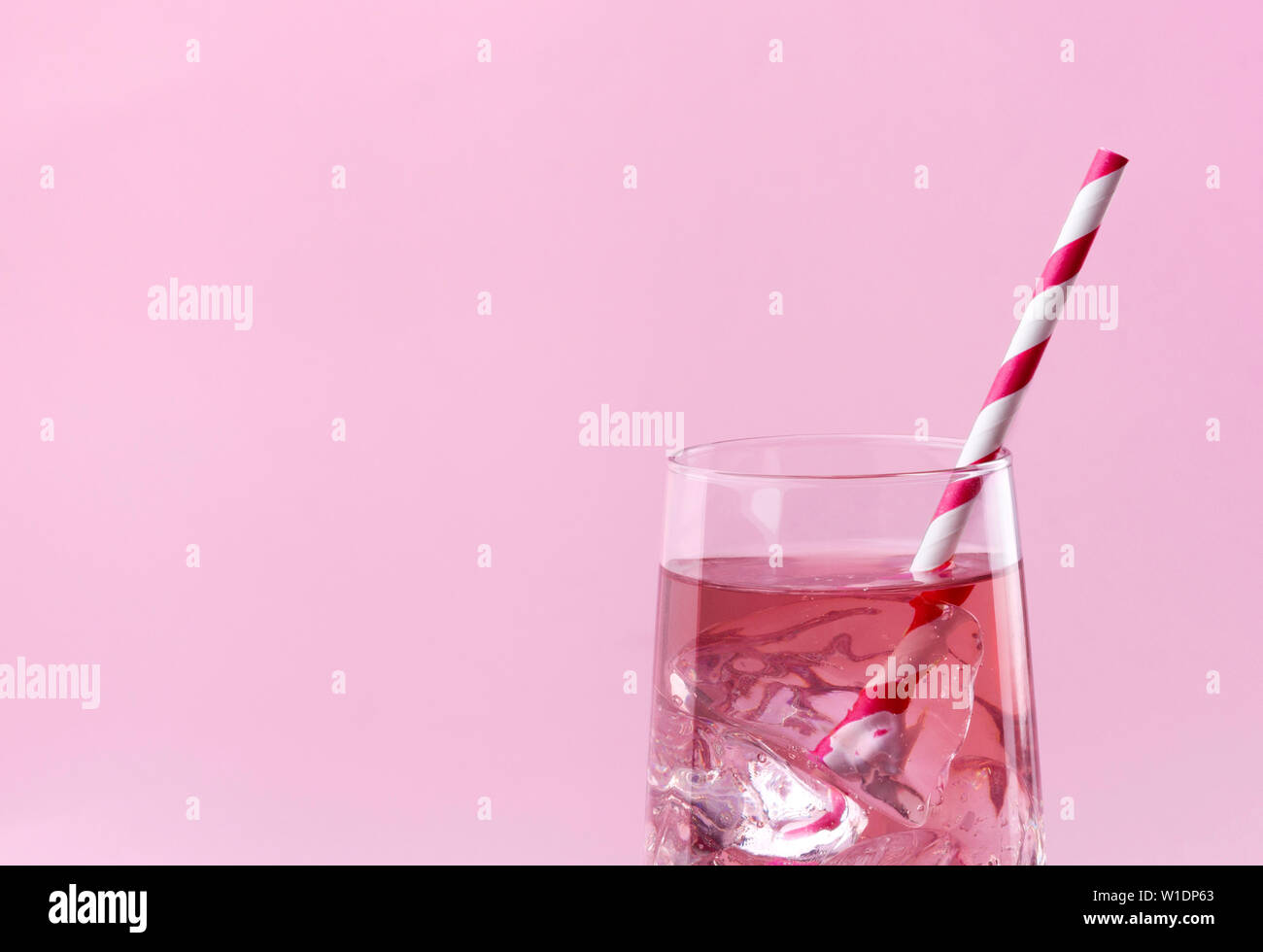 Estate bevande ristoro. Luce rosa rosa cocktail su uno sfondo rosa con strisce rosa paglia. Foto Stock