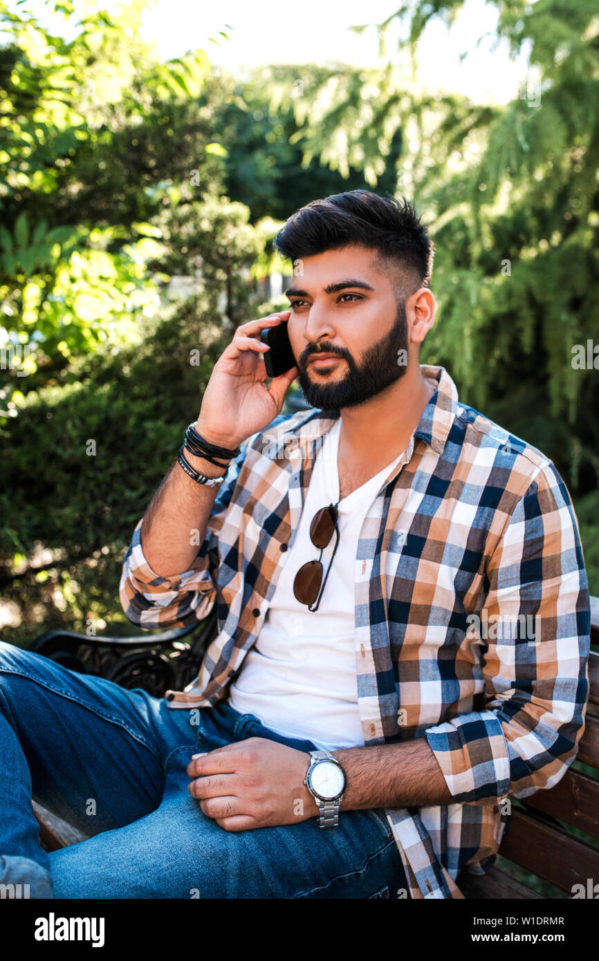 Bel giovane uomo indiano utilizzando il telefono cellulare. Foto Stock