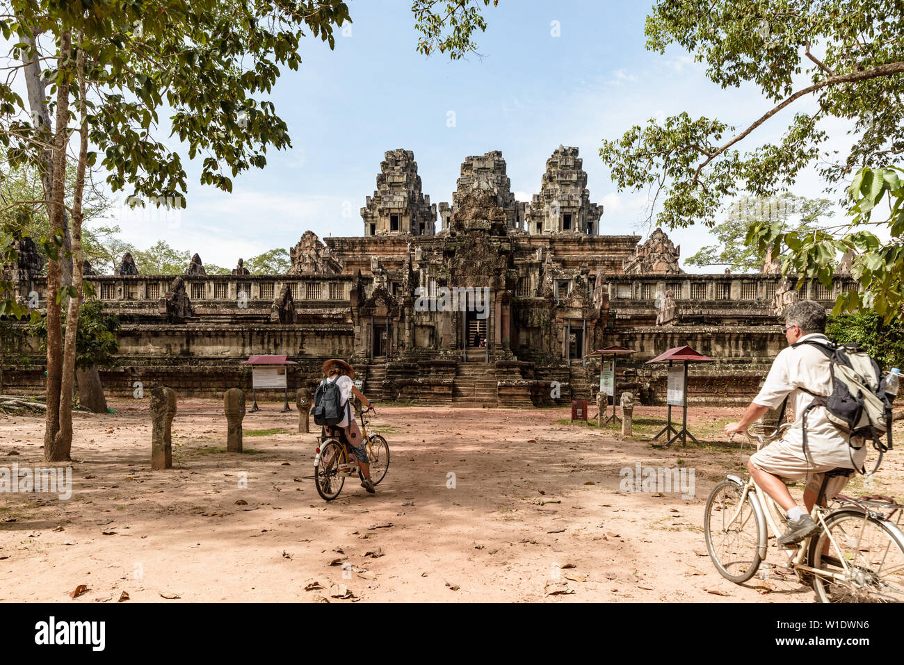 Coppia turistiche Escursioni in bicicletta intorno al tempio di Angkor, Cambogia. Ta Keo costruzione di rovine nella giungla. Eco-turismo viaggi, tonica immagine. Foto Stock