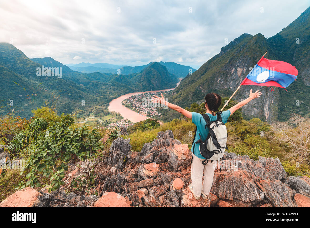 Donna con braccia tese alla conquista vetta a Nong Khiaw Nam Ou River Valley Laos persone mature che viaggiano millenials concetto destinat viaggi Foto Stock