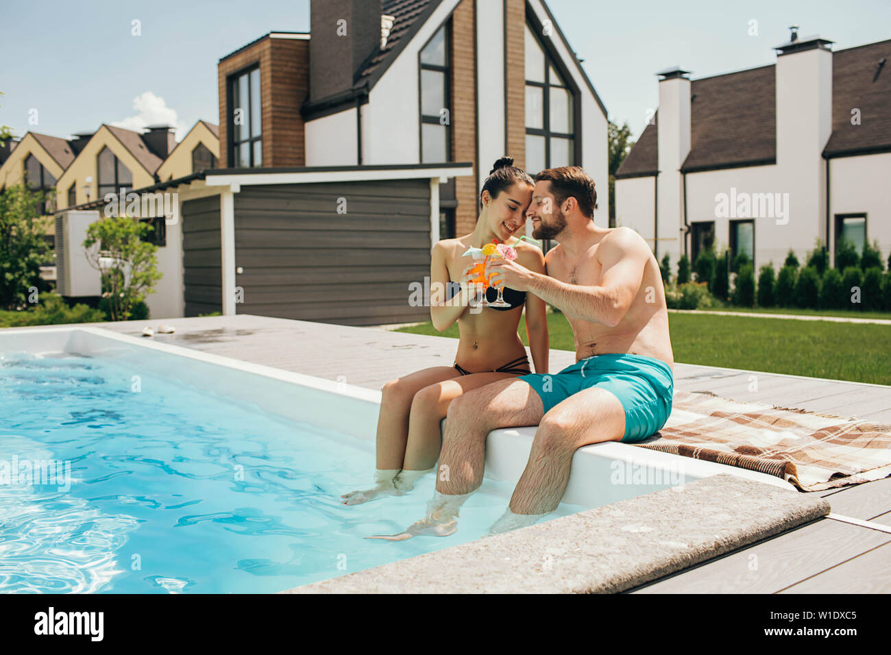 Bella coppia heteroseksual avente estate di riposo. L uomo e la donna seduta vicino alla piscina di acqua e tenendo fresco cocktail Foto Stock