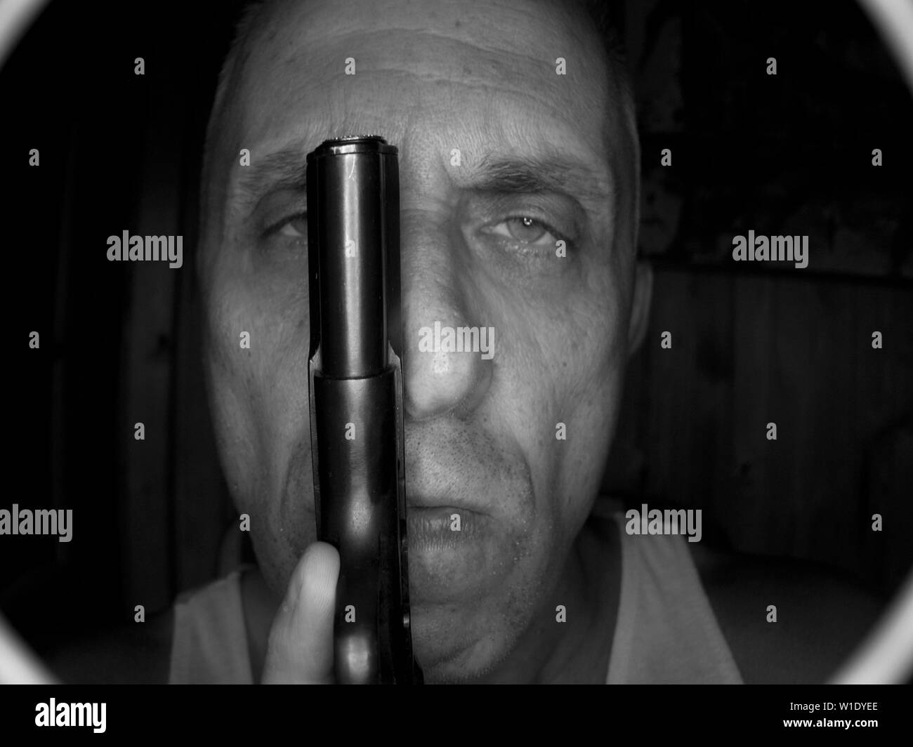 Un uomo in possesso di una pistola, vista attraverso il buco spia o telecamera di videosorveglianza in bianco e nero Foto Stock