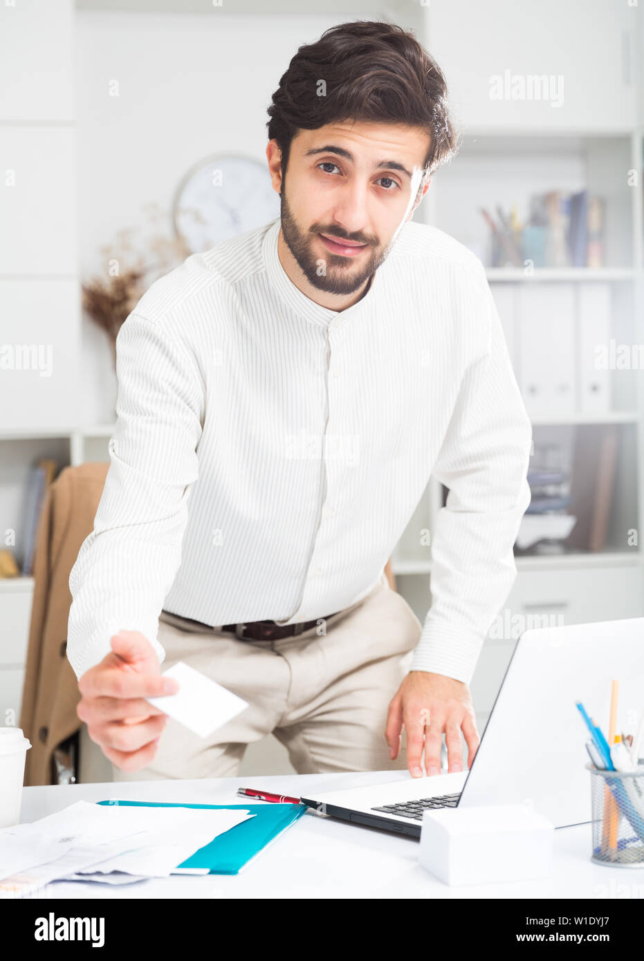 Amichevole maschio giovane lavoratore di ufficio consegna business card in ufficio Foto Stock
