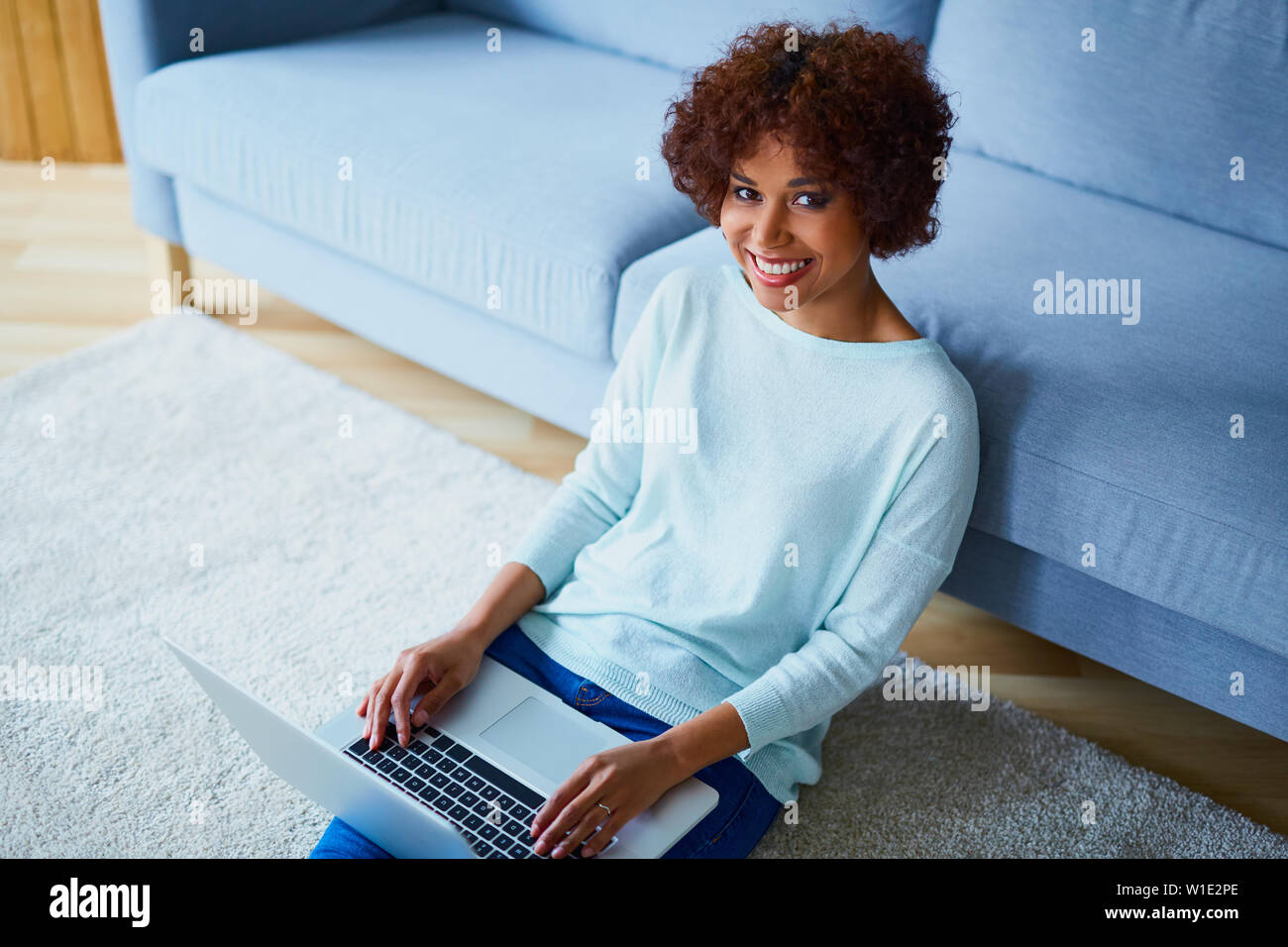 Felice giovane donna africana con laptop seduto in salotto immagine da sopra Foto Stock