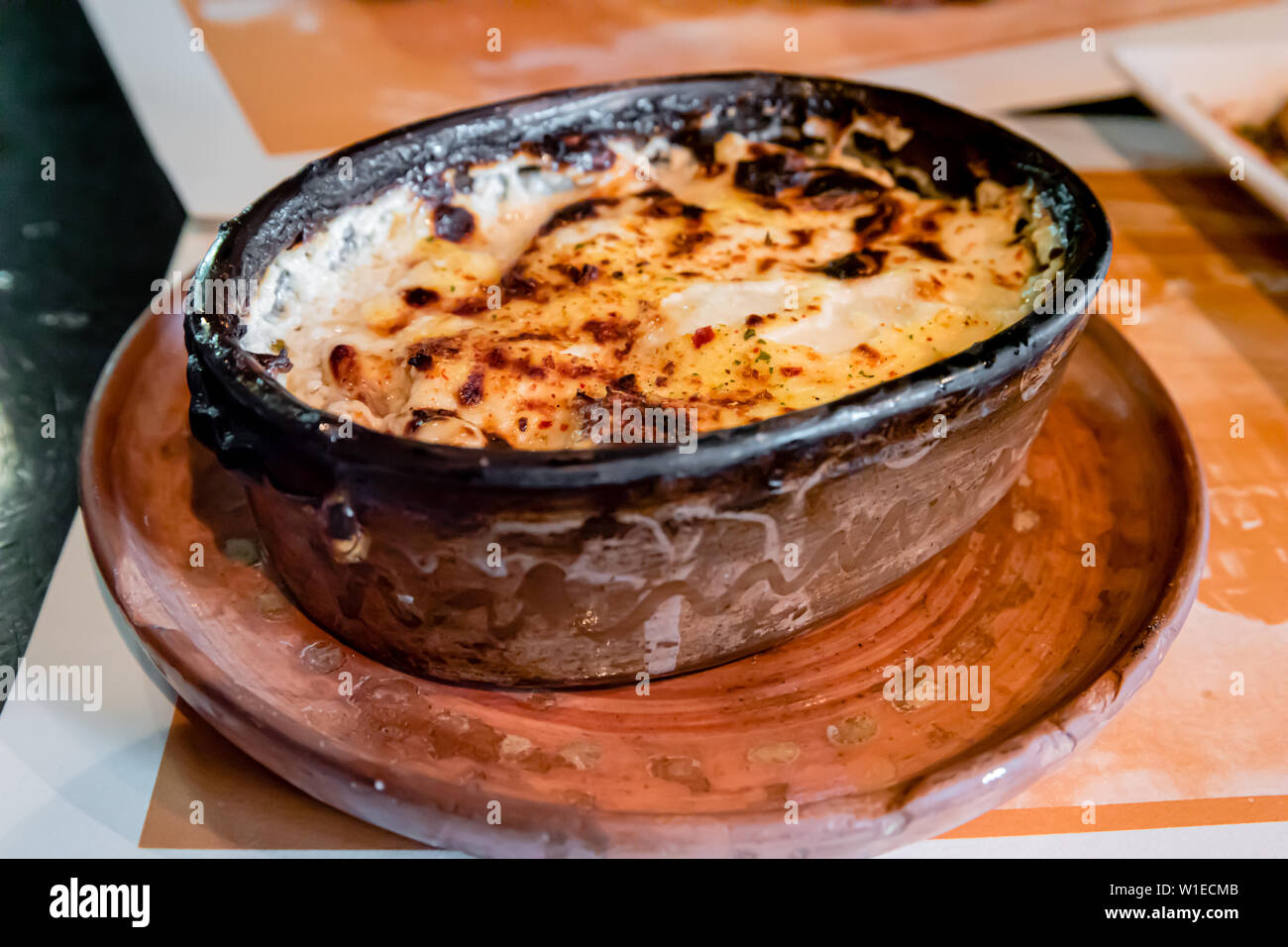 Tradizionale cucina macedone di carni cotte al forno e formaggio in forno (Sirenje vo Furna, o villaggio Pan) - cibo servito nei locali piatto di terracotta Foto Stock