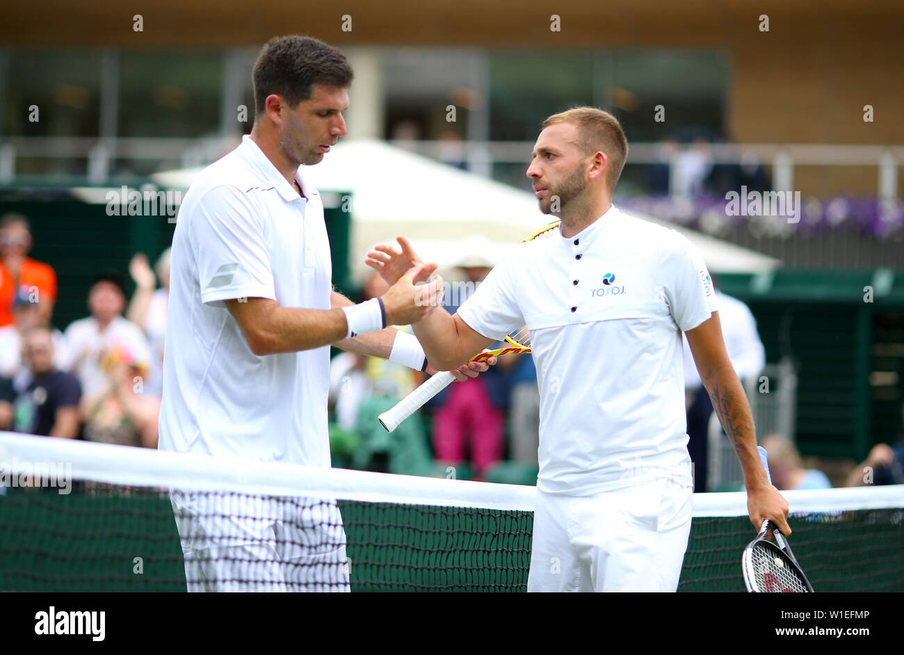 Dan Evans (a destra) scuote le mani con Federico Delbonis dopo aver battuto lui il giorno due dei campionati di Wimbledon al All England Lawn Tennis e Croquet Club di Londra. Foto Stock