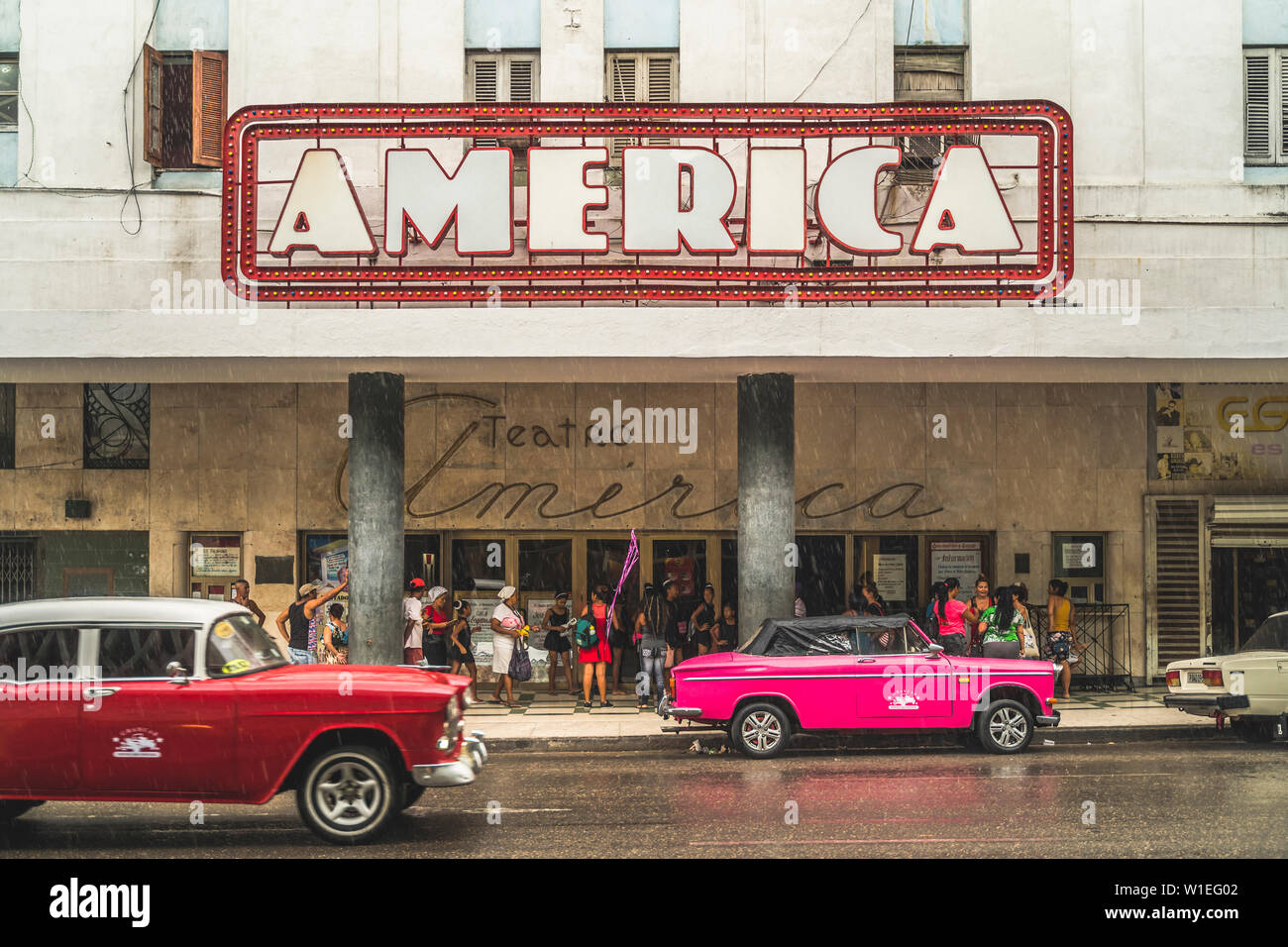 Rosa e Rosso vintage auto al di fuori del Teatro America sotto la pioggia, La Habana (l'Avana, Cuba, West Indies, dei Caraibi e America centrale Foto Stock
