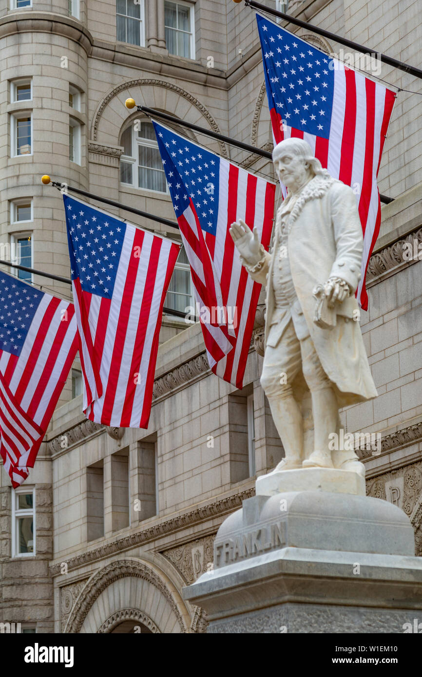 Vista di Benjamin Franklin statua e noi le bandiere di fronte ex Old Post Office Pavilion, Washington D.C., Stati Uniti d'America, America del Nord Foto Stock