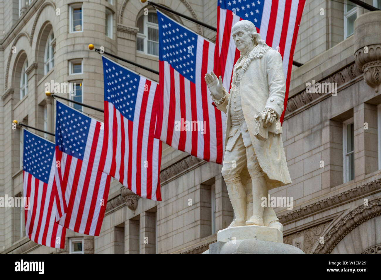 Vista di Benjamin Franklin statua e noi le bandiere di fronte ex Old Post Office Pavilion, Washington D.C., Stati Uniti d'America, America del Nord Foto Stock