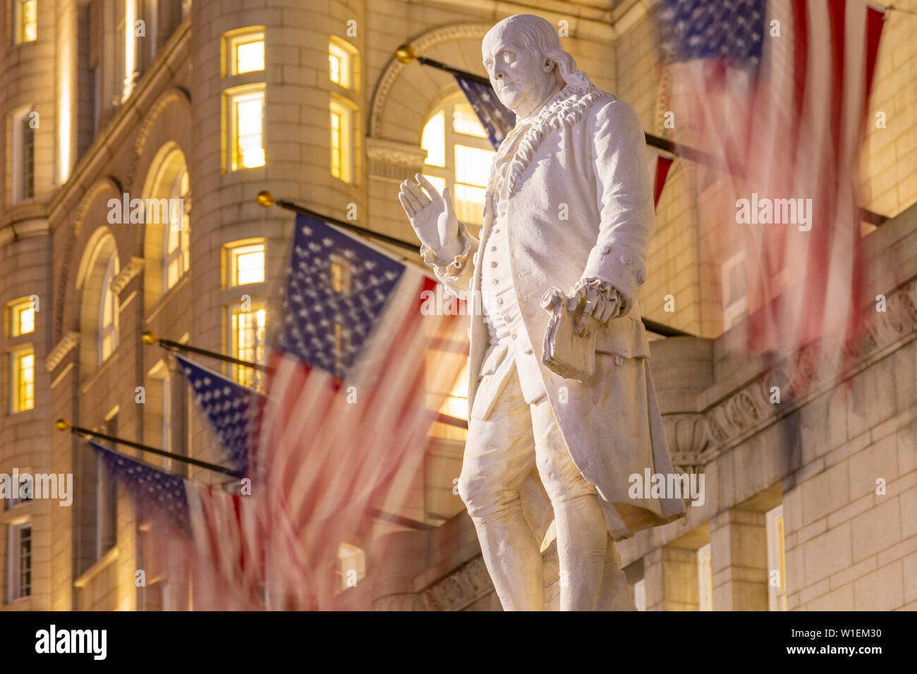 Vista di Benjamin Franklin statua e noi le bandiere di fronte ex Old Post Office Pavilion, Washington D.C., Stati Uniti d'America, America del Nord Foto Stock