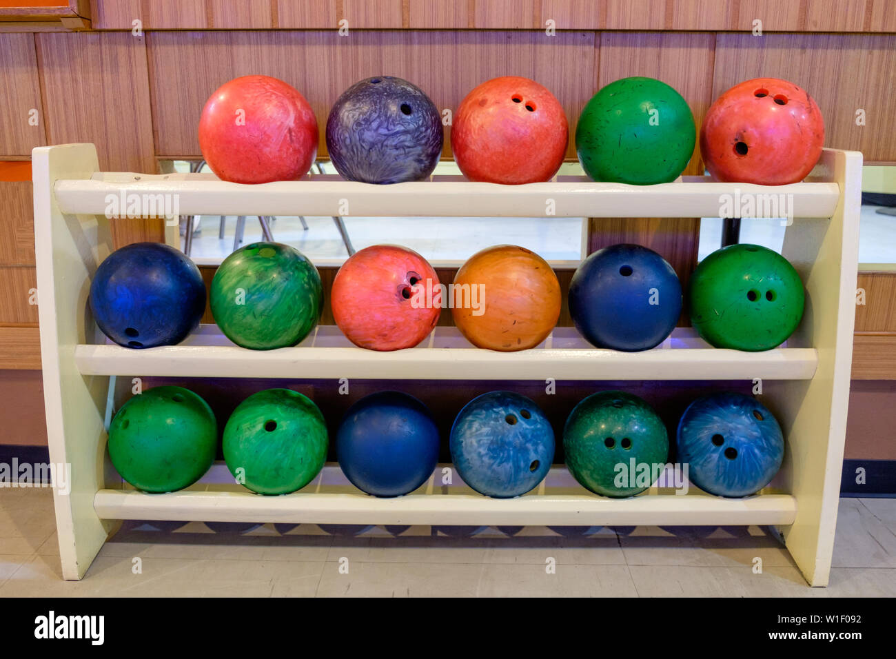 Palle da bowling multi colore riga su rack in legno Foto Stock