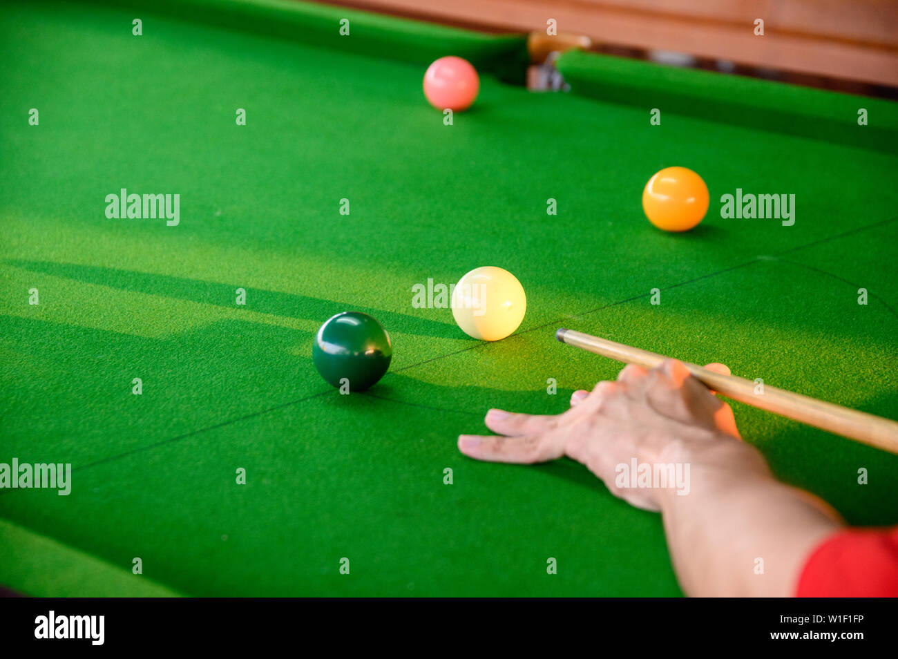 Mano d'uomo giocare biliardo nel bar con colore sfera da biliardo Foto Stock
