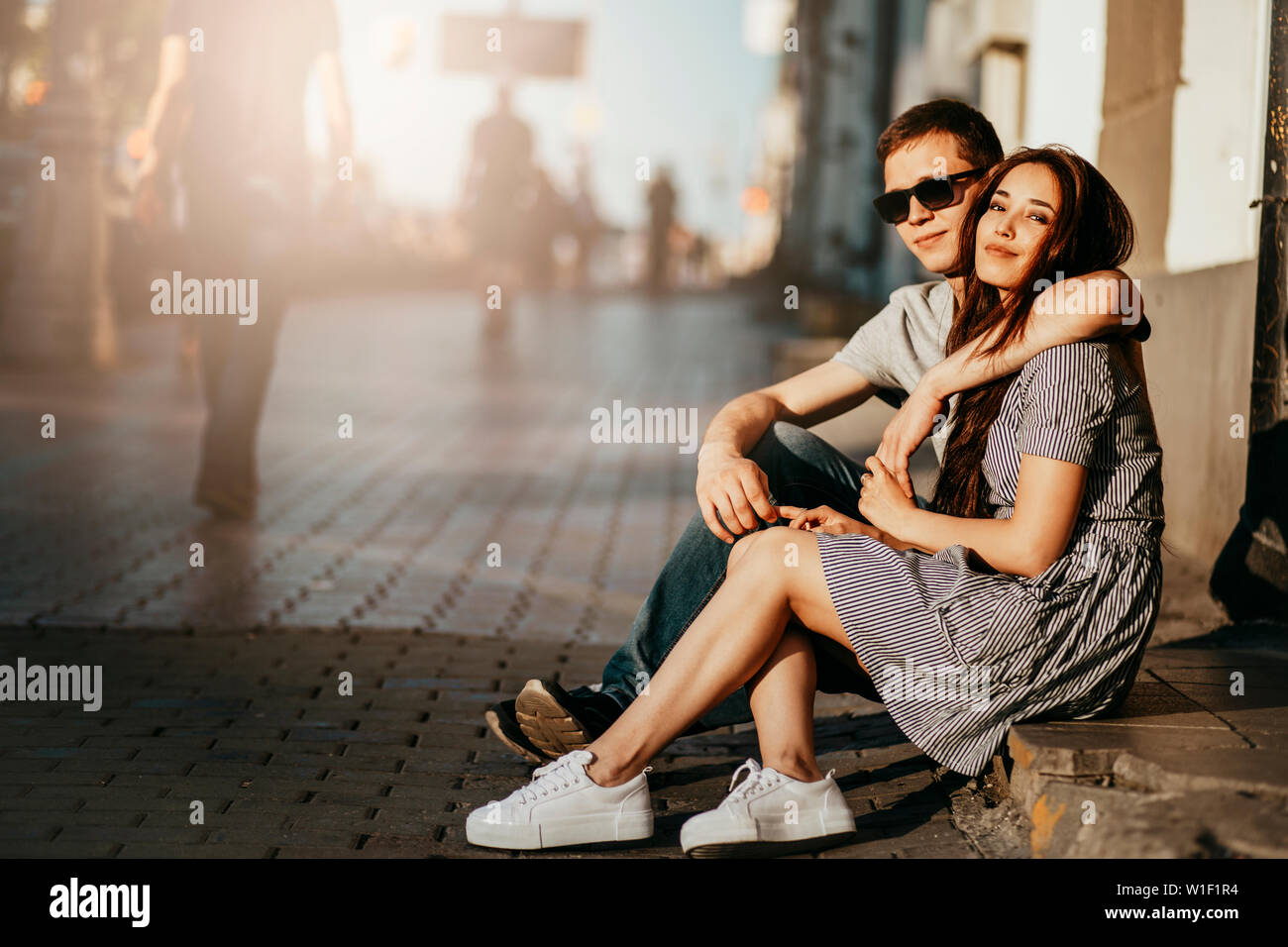 Felice coppia giovane in amore adolescenti amici vestiti in stile casual  seduti insieme sulla strada di città Foto stock - Alamy
