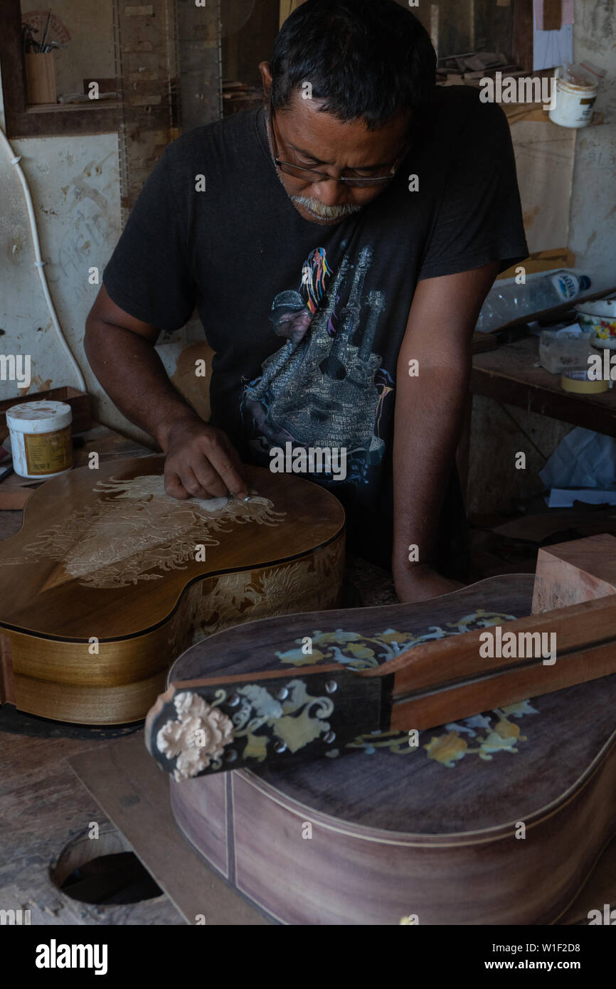 GIANYAR,BALI/INDONESIA-30 MAGGIO 2019: una chitarra artigiano sono carving a chitarre classiche in legno in una chitarra in legno officina di proprietà di I Wayan rimorchiatore Foto Stock