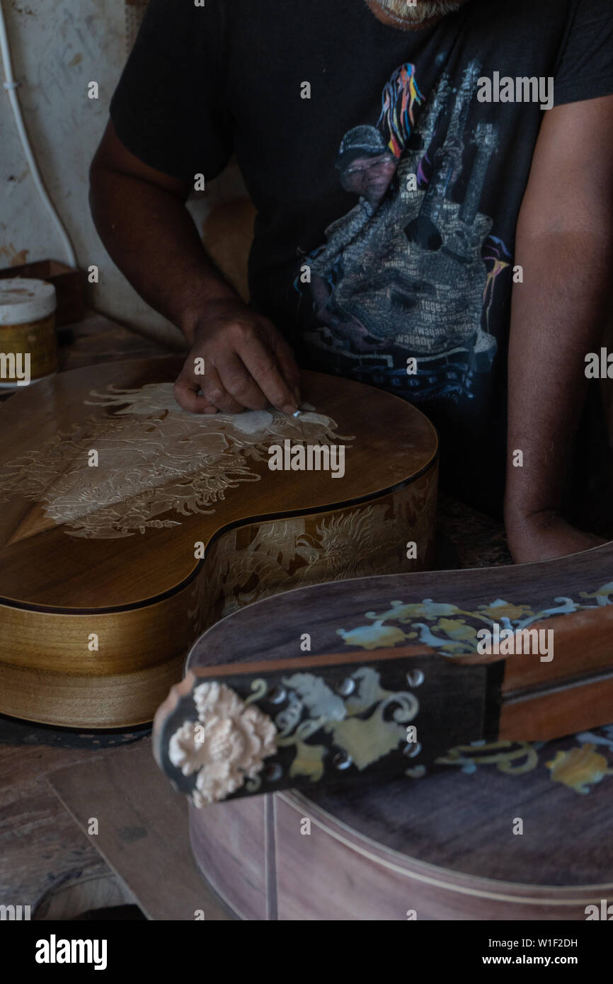 Una chitarra artigiano sono carving a chitarre classiche in legno, con pattern balinese, in una chitarra in legno workshop presso Guwang Village, Gianyar Bali Foto Stock