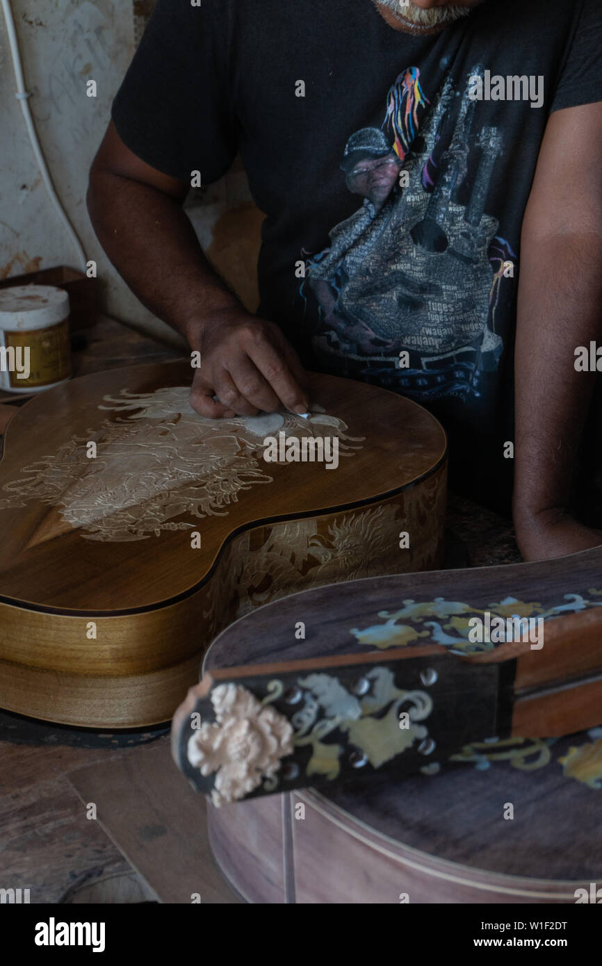 Una chitarra artigiano sono carving a chitarre classiche in legno, con pattern balinese, in una chitarra in legno workshop presso Guwang Village, Gianyar Bali Foto Stock