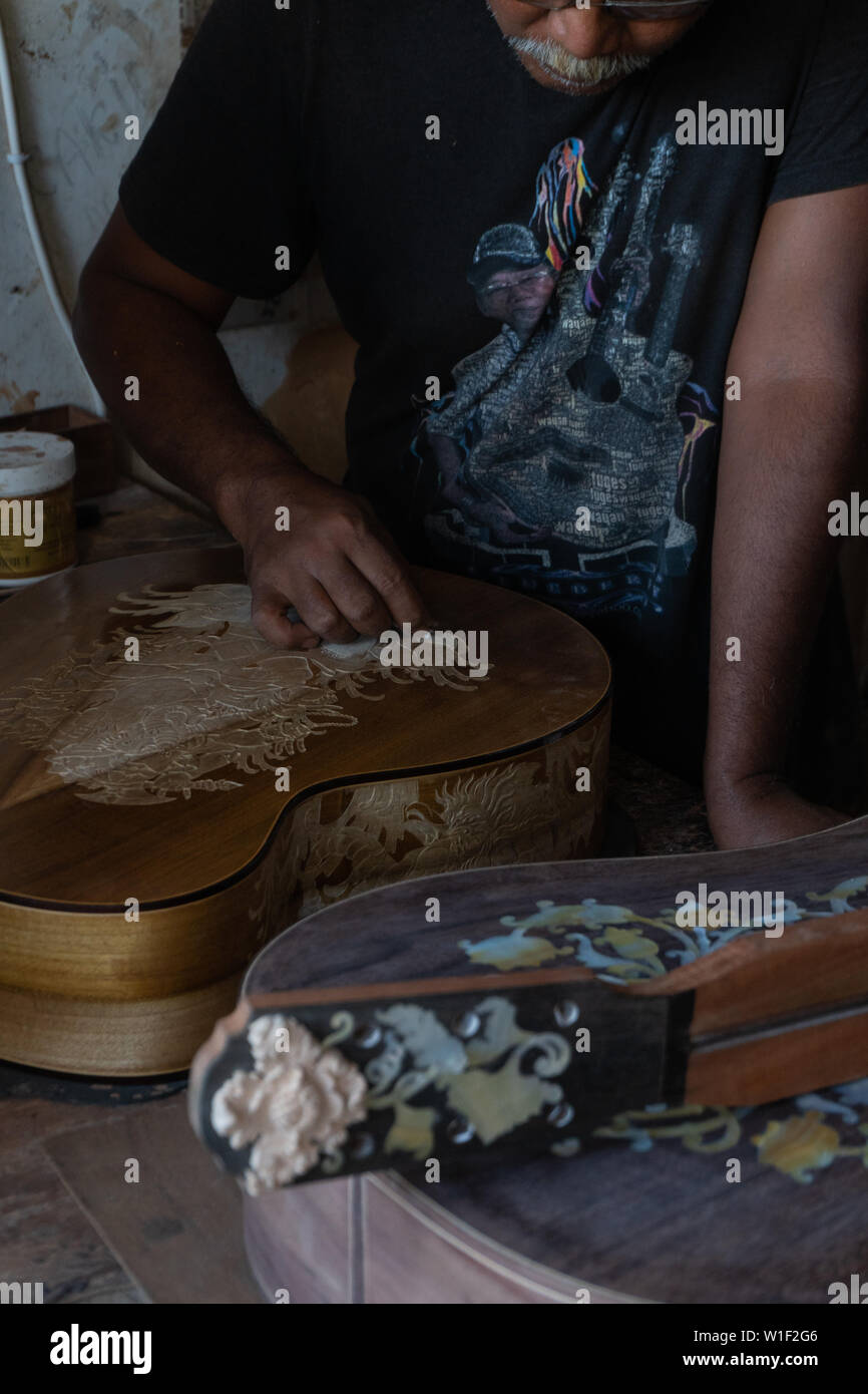 Una chitarra artigiano sono carving a chitarre classiche in legno, con pattern balinese, in una chitarra in legno workshop presso Guwang Village, Gianyar Bali Foto Stock