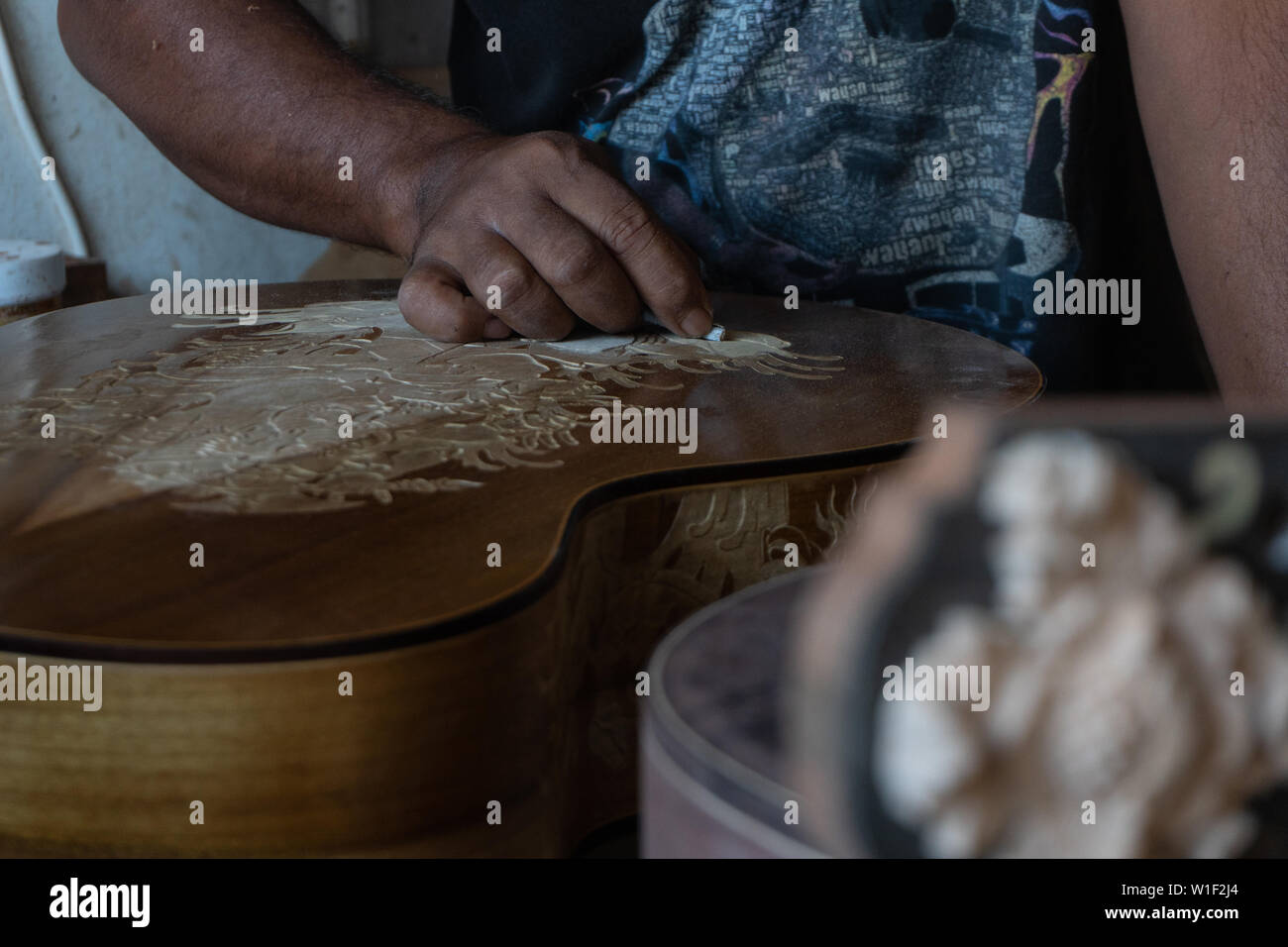 Una chitarra artigiano sono carving a chitarre classiche in legno, con pattern balinese, in una chitarra in legno workshop presso Guwang Village, Gianyar Bali Foto Stock