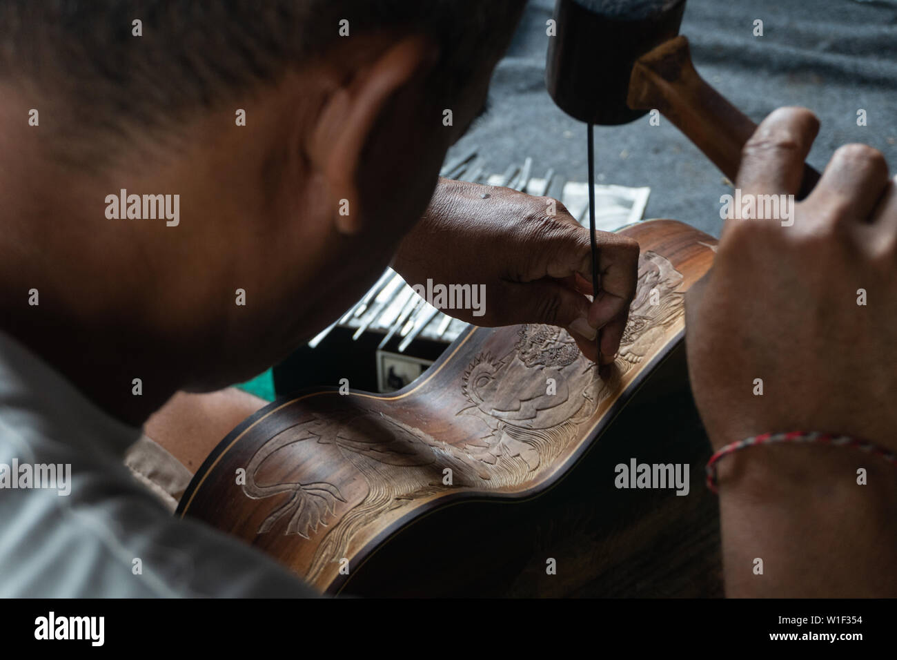 Una chitarra artigiano sono carving a chitarre classiche in legno, con pattern balinese, in una chitarra in legno workshop presso Guwang Village, Gianyar Bali Foto Stock