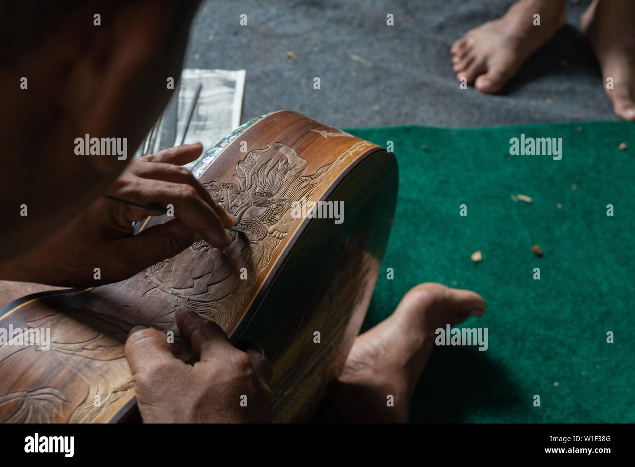 Una chitarra artigiano sono carving a chitarre classiche in legno, con pattern balinese, in una chitarra in legno workshop presso Guwang Village, Gianyar Bali Foto Stock