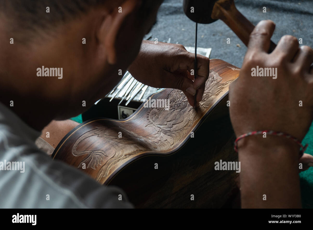 Una chitarra artigiano sono carving a chitarre classiche in legno, con pattern balinese, in una chitarra in legno workshop presso Guwang Village, Gianyar Bali Foto Stock