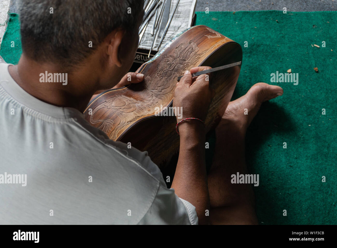 Una chitarra artigiano sono carving a chitarre classiche in legno, con pattern balinese, in una chitarra in legno workshop presso Guwang Village, Gianyar Bali Foto Stock