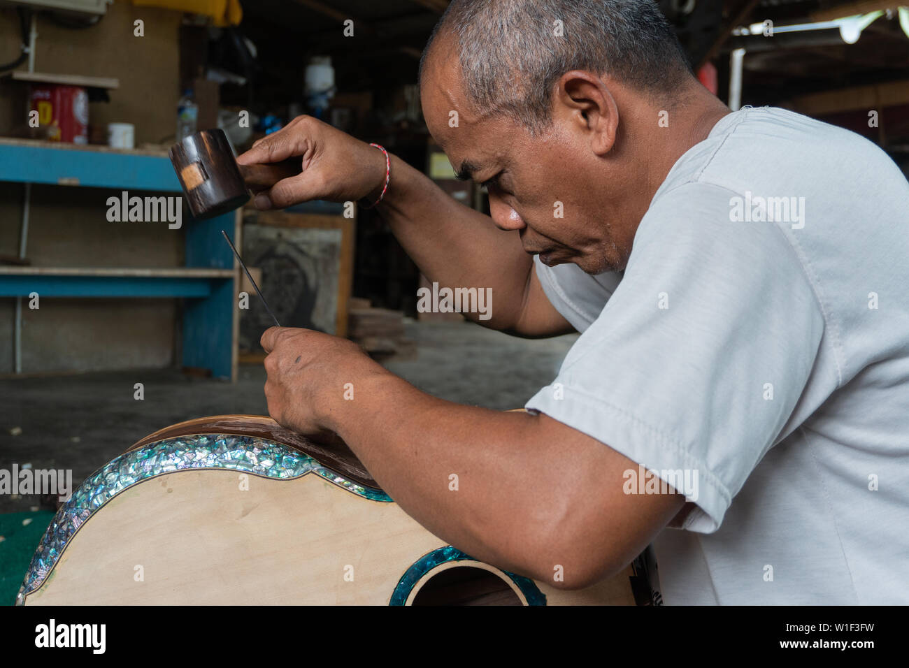 GIANYAR,BALI/INDONESIA-30 MAGGIO 2019: una chitarra artigiano sono carving a chitarre classiche in legno in una chitarra in legno officina di proprietà di I Wayan rimorchiatore Foto Stock