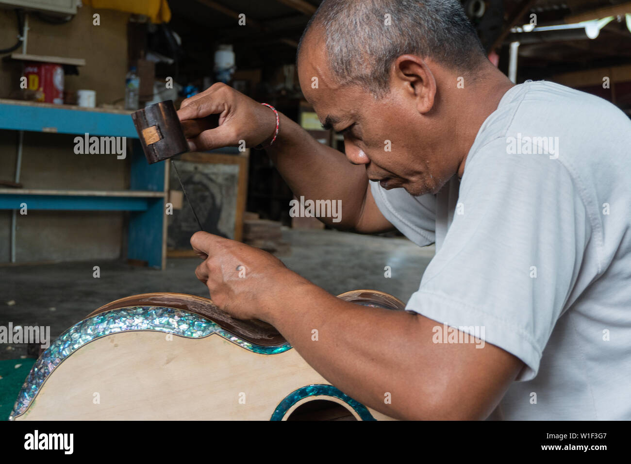 GIANYAR,BALI/INDONESIA-30 MAGGIO 2019: una chitarra artigiano sono carving a chitarre classiche in legno in una chitarra in legno officina di proprietà di I Wayan rimorchiatore Foto Stock
