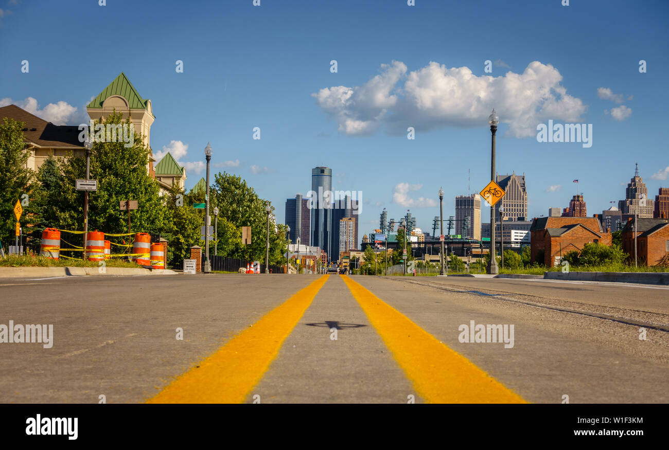 Un vuoto che la strada attraverso una vecchia città di Detroit quartiere con edifici del centro in background Foto Stock