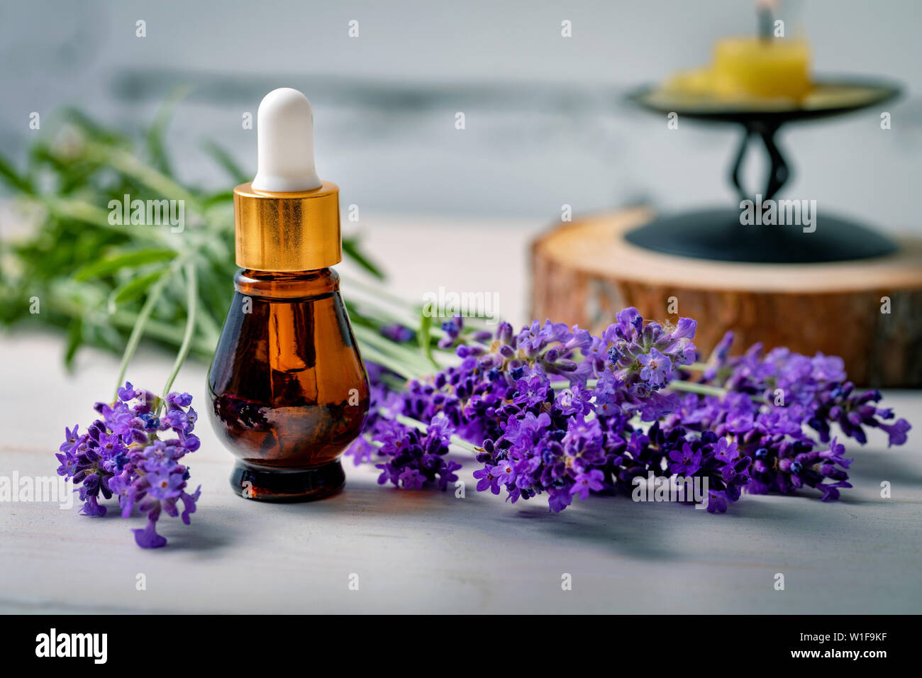 Aromaterapia - l'olio essenziale di lavanda bottiglia con fiori freschi di ramoscelli e candela Foto Stock