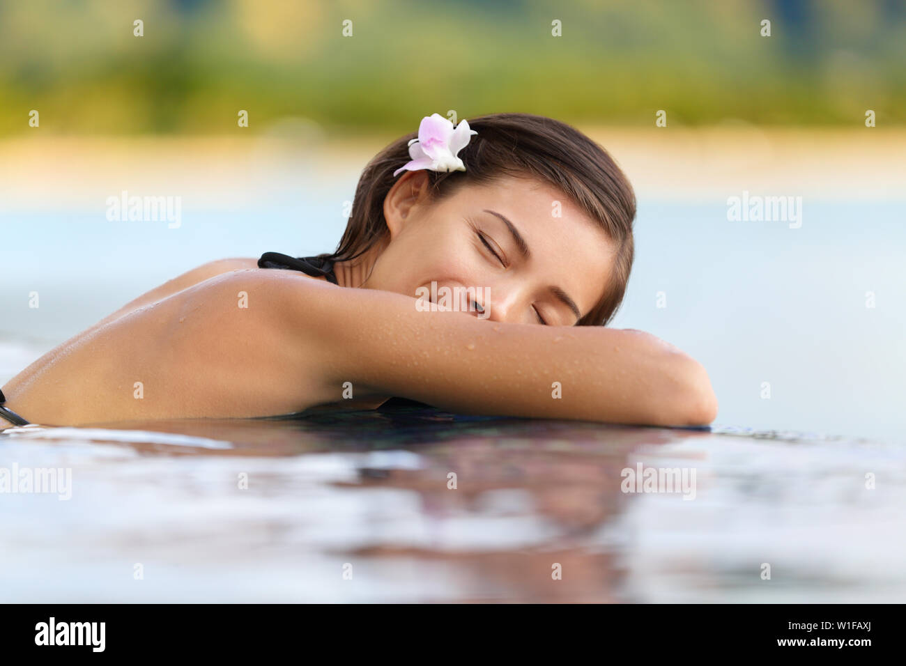 Donna di relax in hotel di lusso piscina sulle vacanze - Vacanze viaggi. Asian femmina giovane persona che dormiva nella piscina spa presso hotel resort in un rifugio esotico. Foto Stock