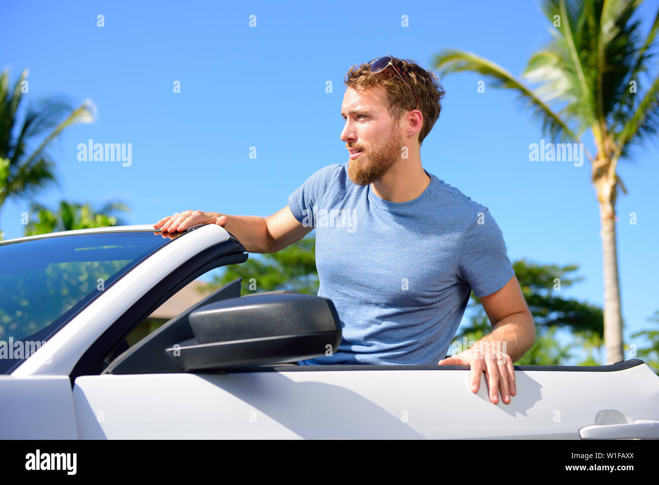Tanga uomo urbano ritratto con cool autovettura convertibile in estate viaggio su strada. Giovane adulto seduto nel suo nuovo noleggio auto cercando felice. Foto Stock