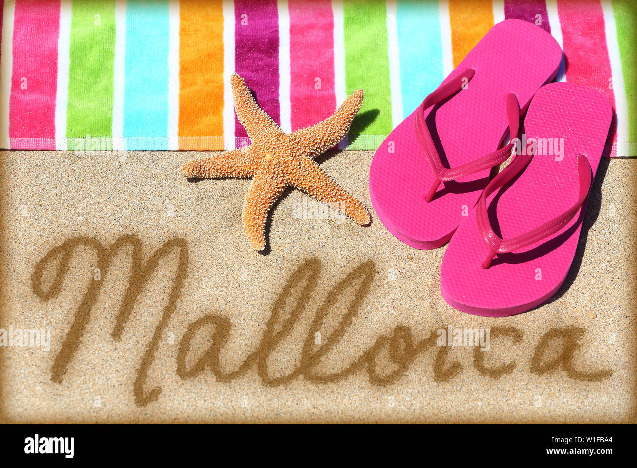 Mallorca beach concetto di viaggio. MALLORCA scritto in sabbia con acqua  vicino al telo da spiaggia e sandali estivi e stelle marine. Vacanza Spagna  vacanze concetto. Maiorca, isole Baleari, Spagna Foto stock -