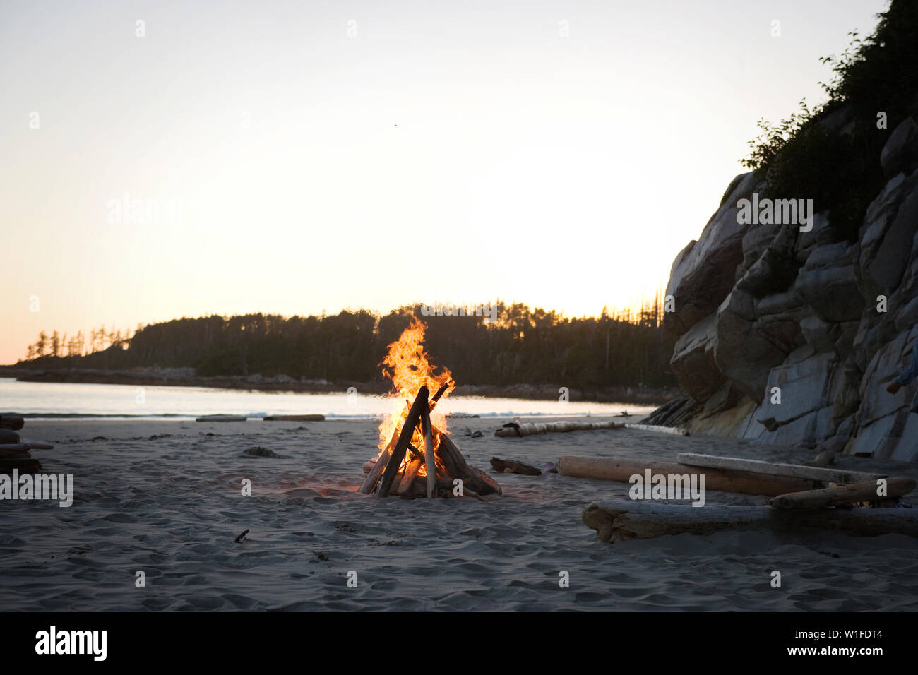Il falò in una remota spiaggia sabbiosa al crepuscolo. Foto Stock