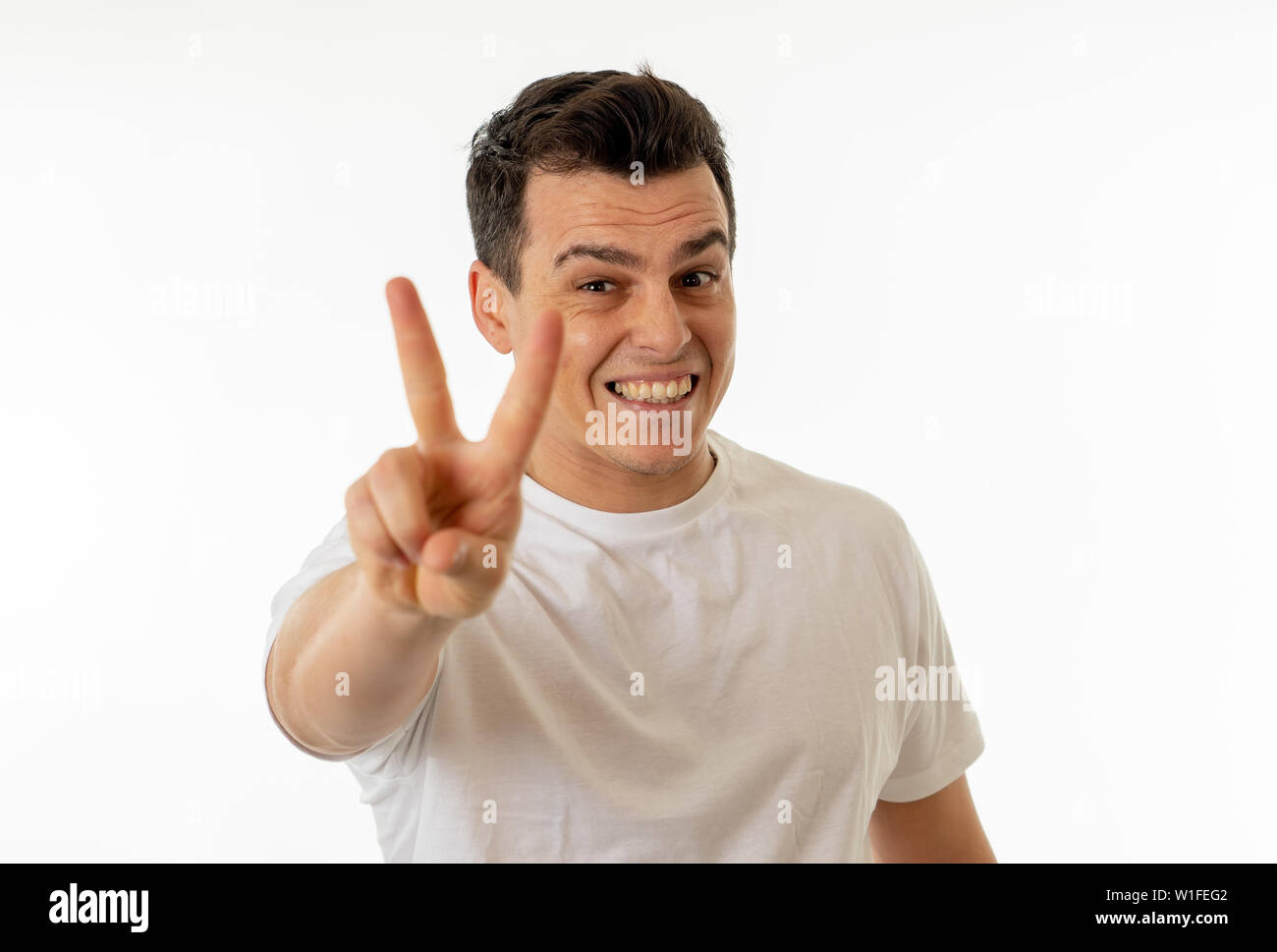 Close up ritratto di Giovane uomo caucasico con un buon viso e sorriso bellissimo che mostra la vittoria gesti. Isolato su sfondo bianco. In Persone, Posi Foto Stock